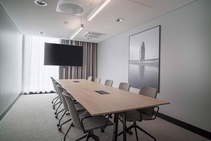 Meeting room with long table, TV in front of the window and large photograph hanging on the wall