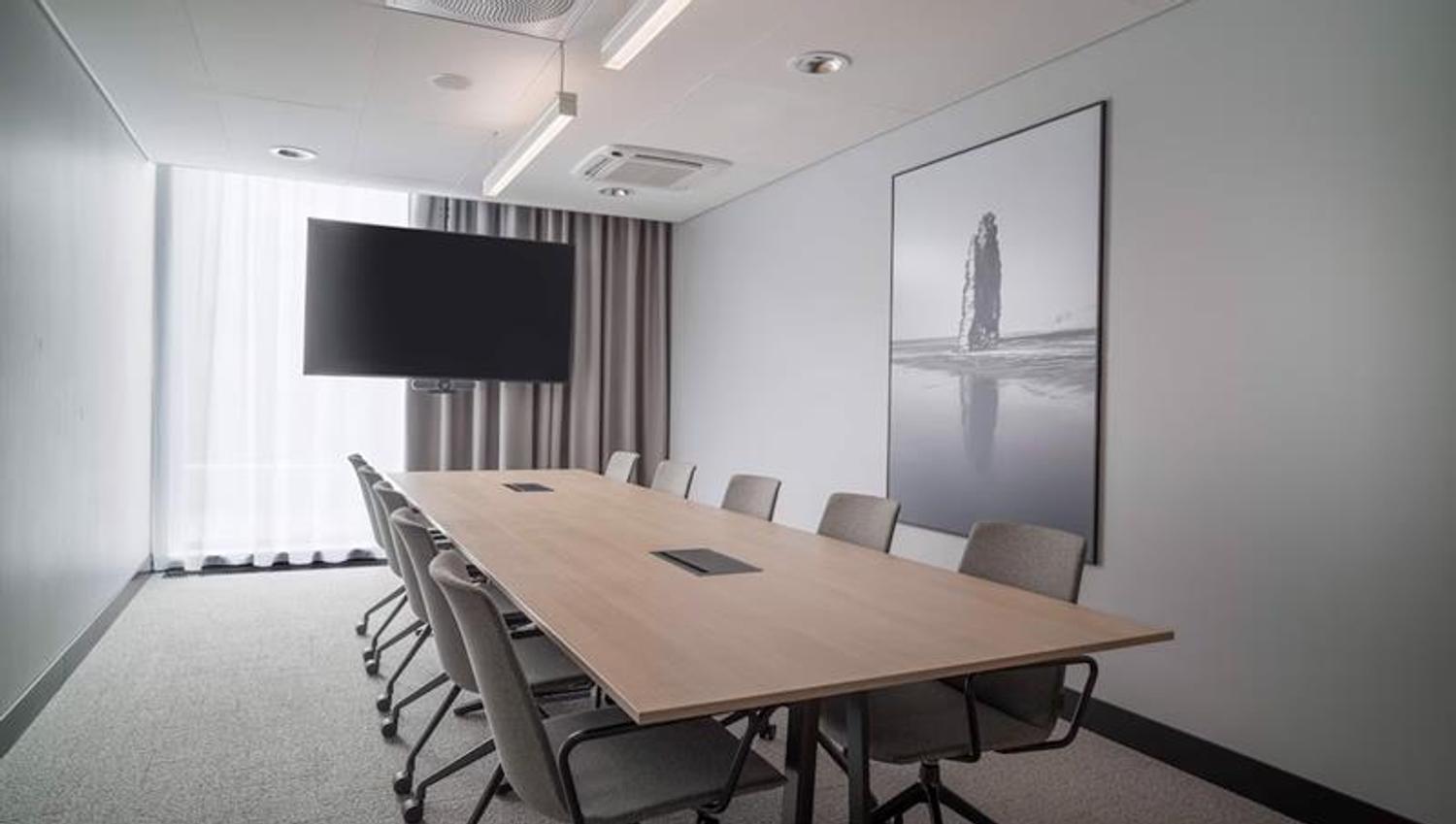 Meeting room with long table, TV in front of the window and large photograph hanging on the wall