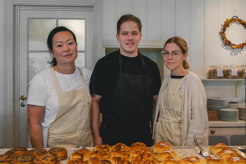 A few of the bakery staff posing behind a table of baked goods.