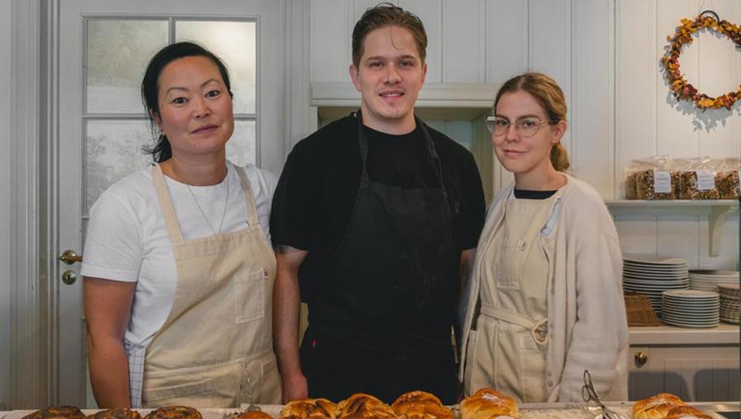 A few of the bakery staff posing behind a table of baked goods.