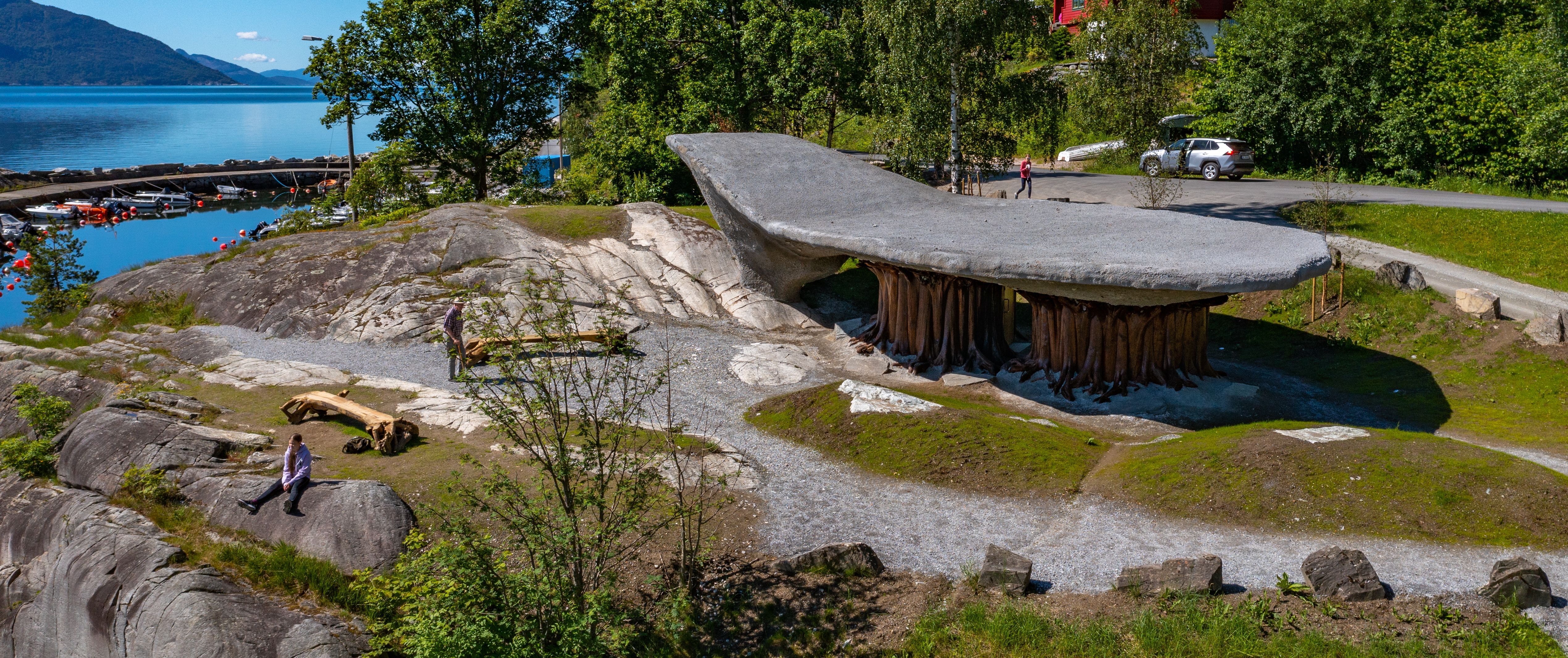 Image of Tyrvefjøra, a unique rest stop designed like an inverted boat, nestled in the Scandinavian landscape with views of a fjord and mountains in N
