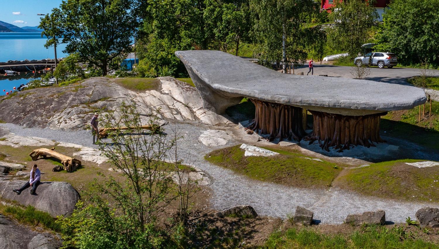 Image of Tyrvefjøra, a unique rest stop designed like an inverted boat, nestled in the Scandinavian landscape with views of a fjord and mountains in N