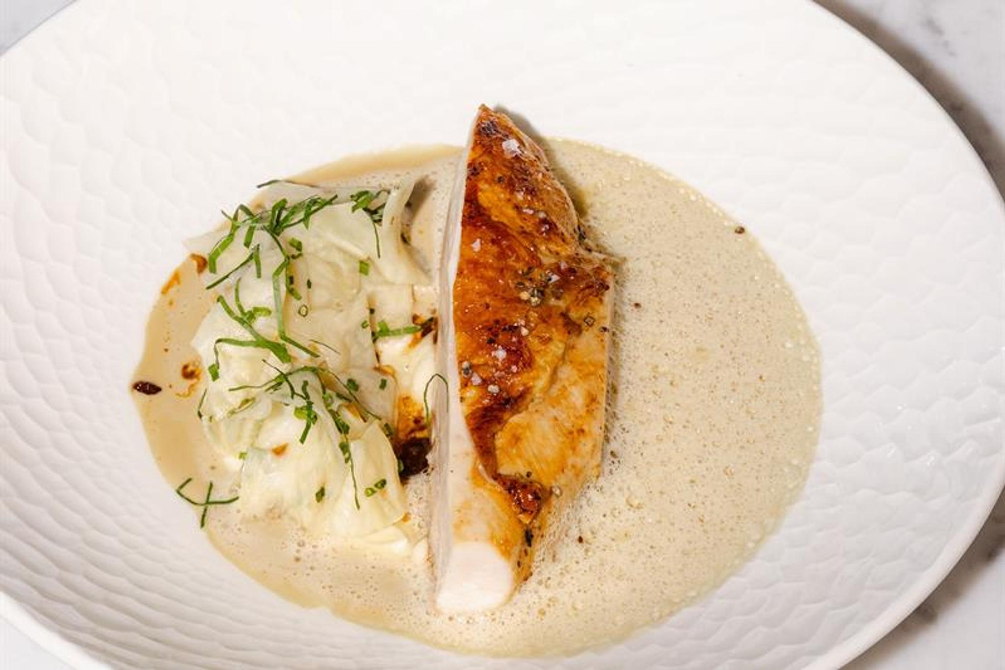 Detail of turkey in gravy on a white plate, with a bowl of potatoes on the side.