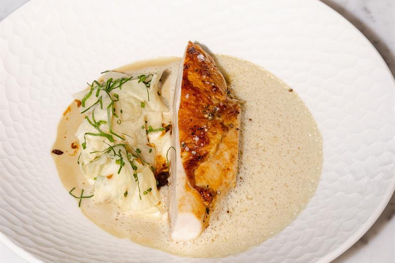 Detail of turkey in gravy on a white plate, with a bowl of potatoes on the side.