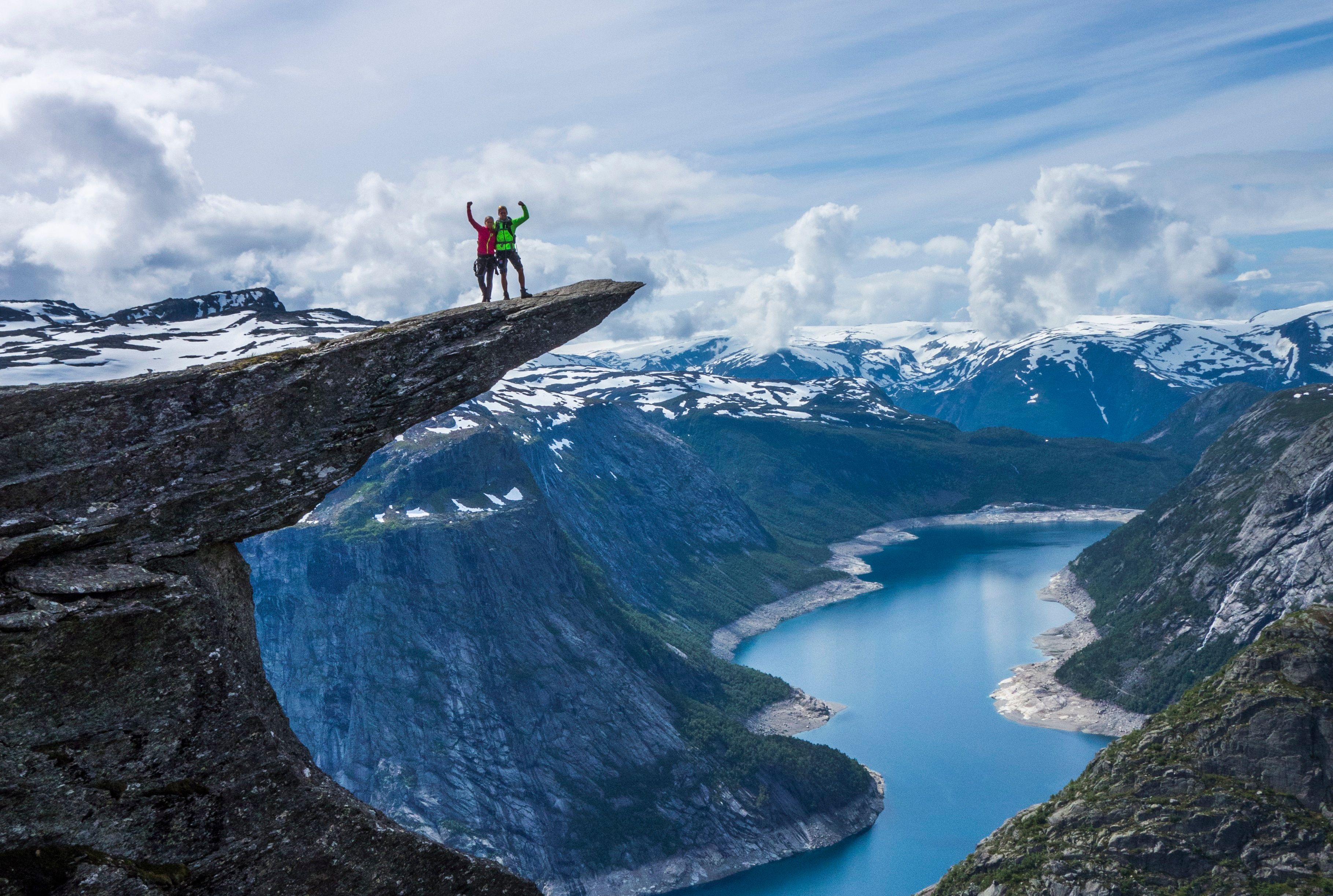 Two people standing on Trolltunga. 