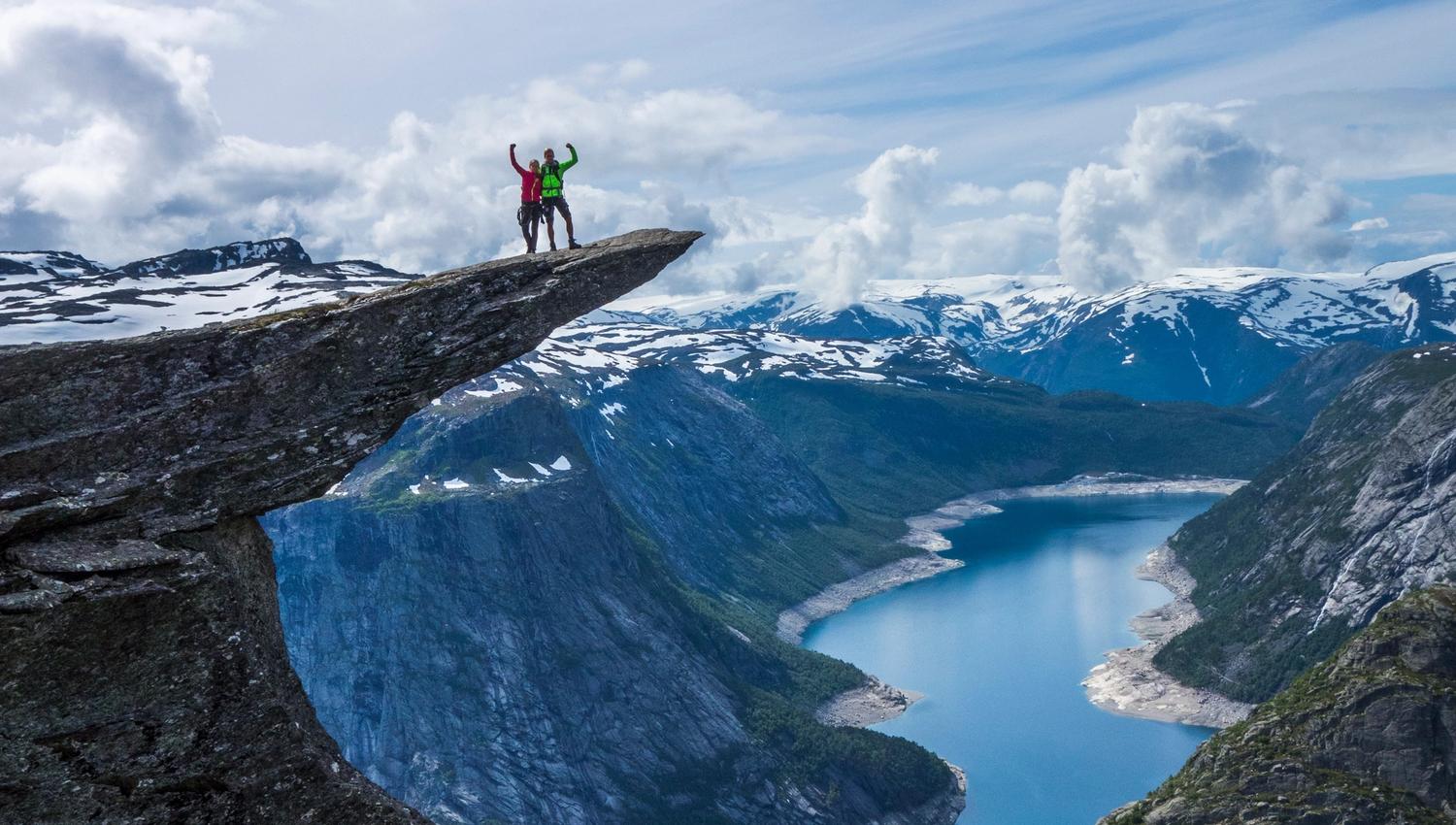 Two people standing on Trolltunga.