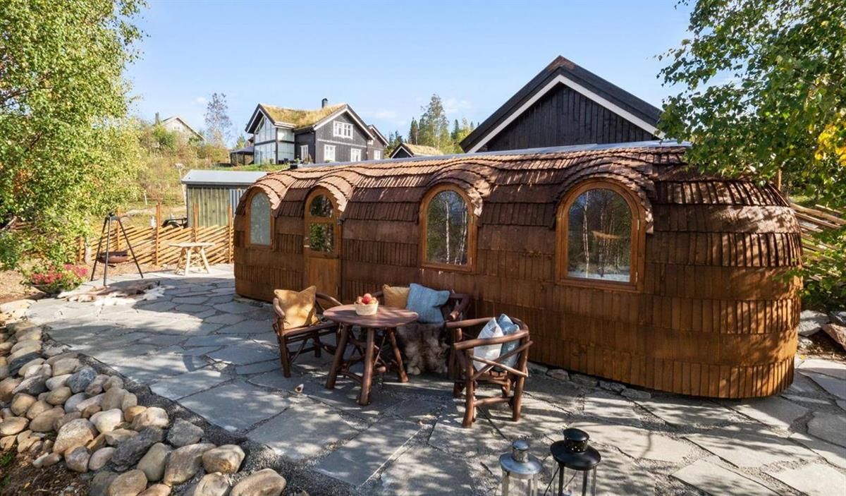 An outdoor area with wooden structures and seating, surrounded by stones and trees.