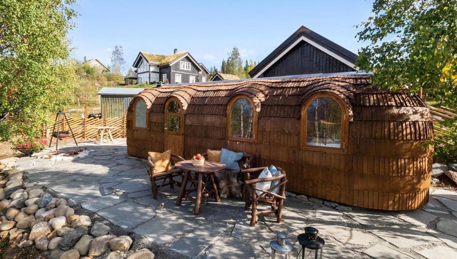 An outdoor area with wooden structures and seating, surrounded by stones and trees.