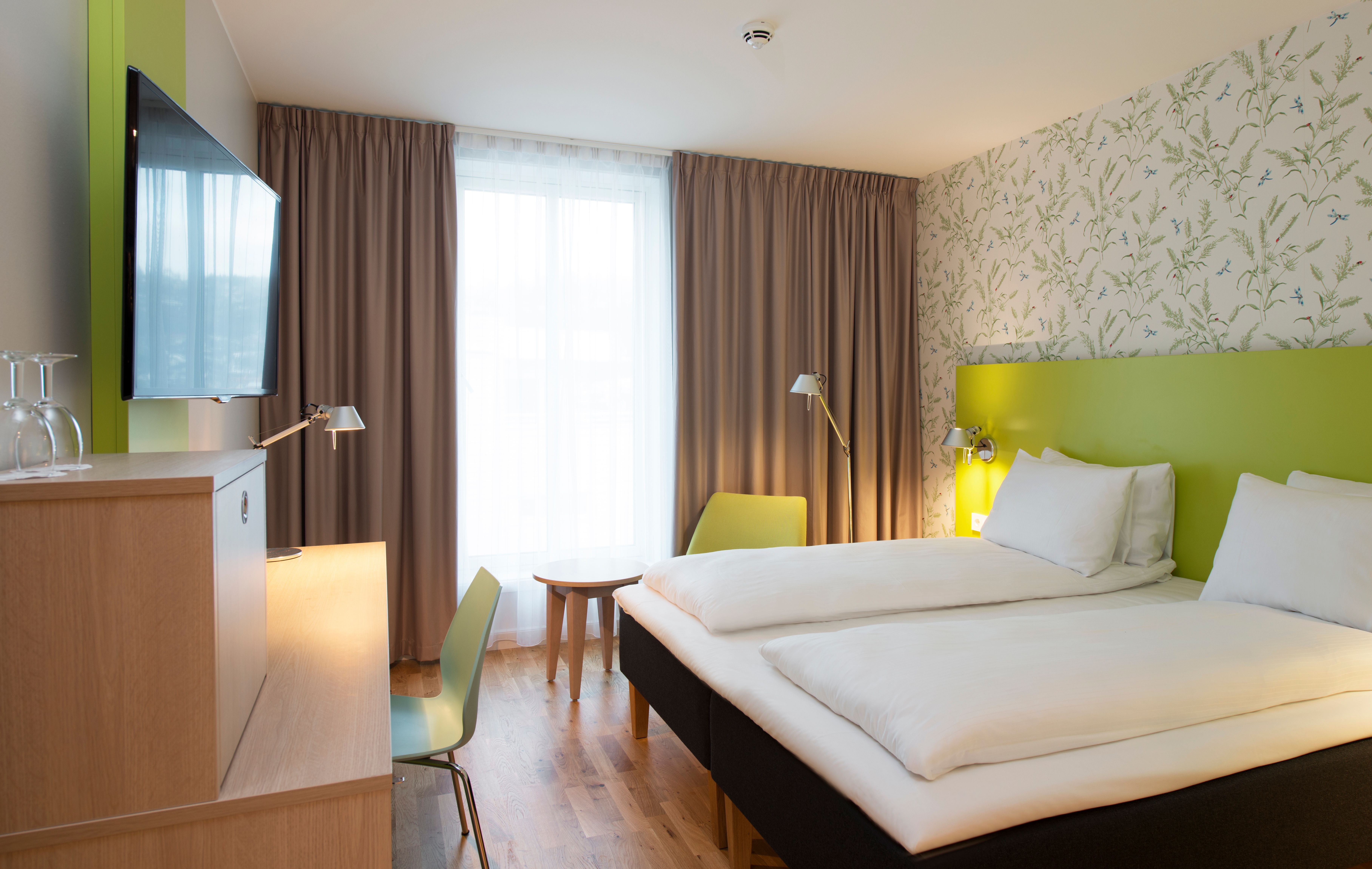 Comfortable hotel room at Thon Hotel Sandven, featuring modern design and an inviting atmosphere.