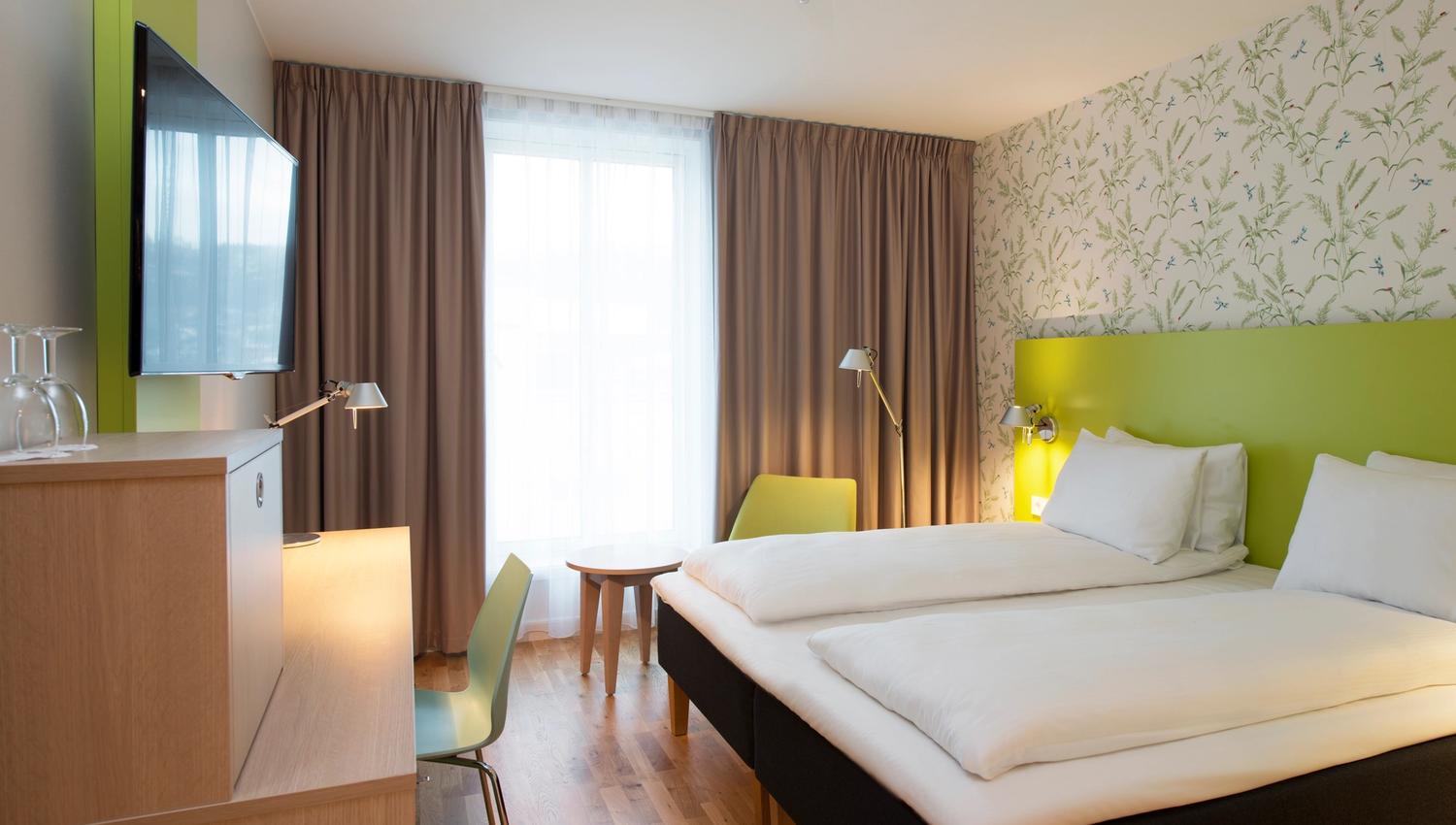 Comfortable hotel room at Thon Hotel Sandven, featuring modern design and an inviting atmosphere.