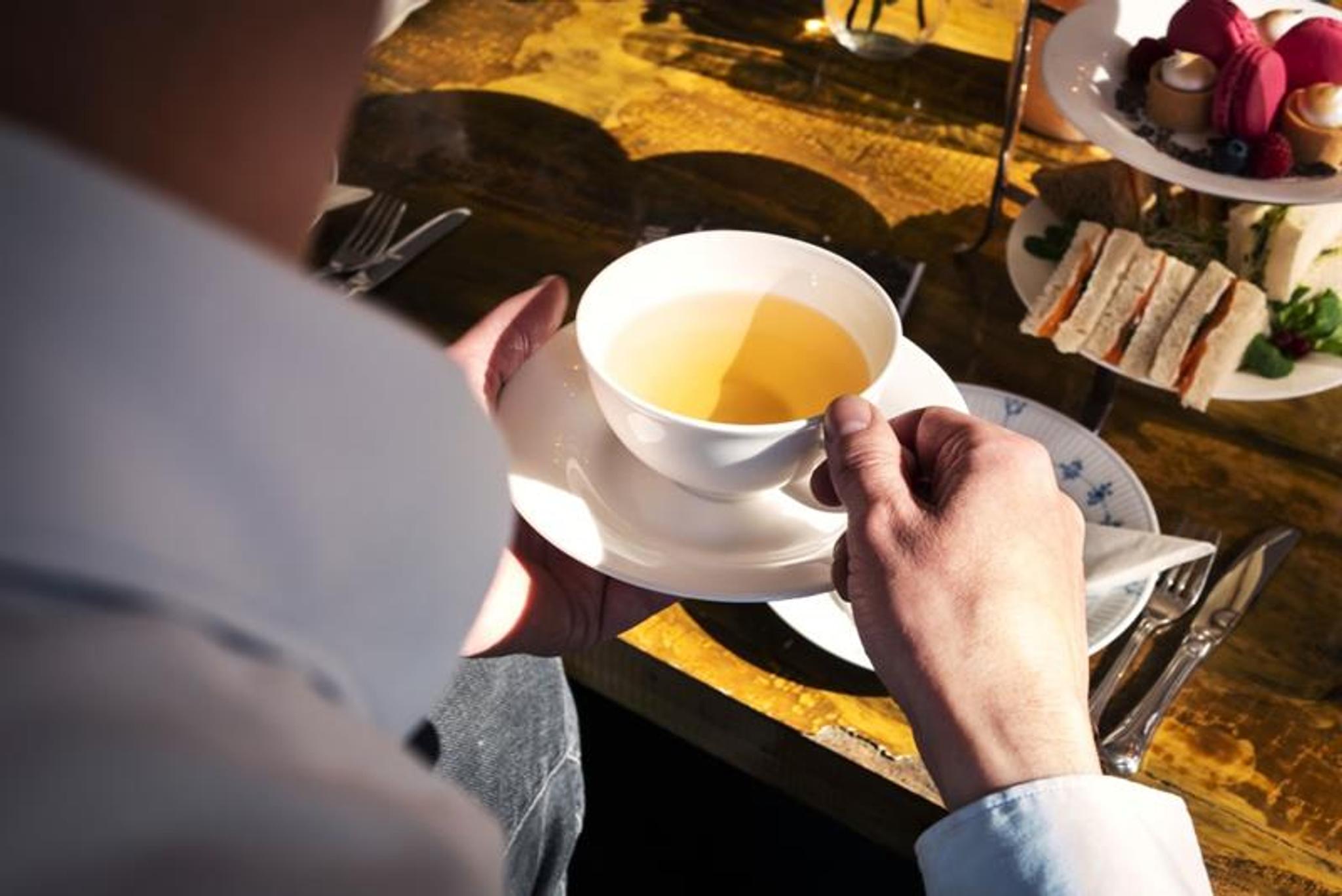 Detail photo of a man holding a cup of tea.