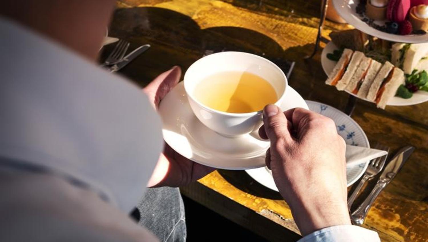 Detail photo of a man holding a cup of tea.