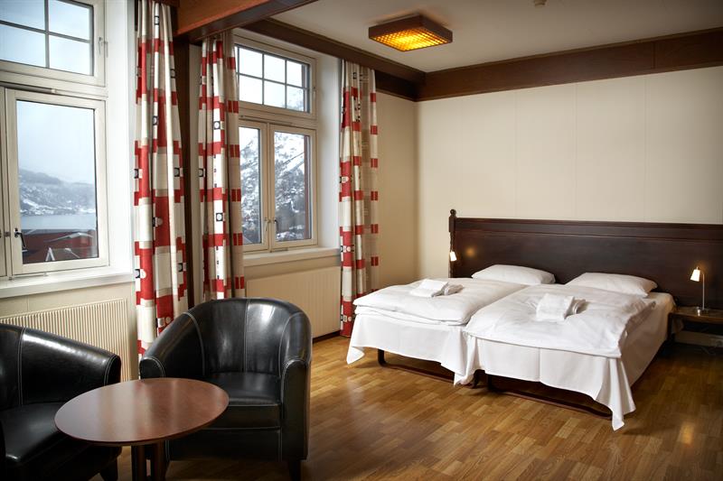 Spacious hotel room with large windows, classic decor, and views of the Hardangerfjord.

