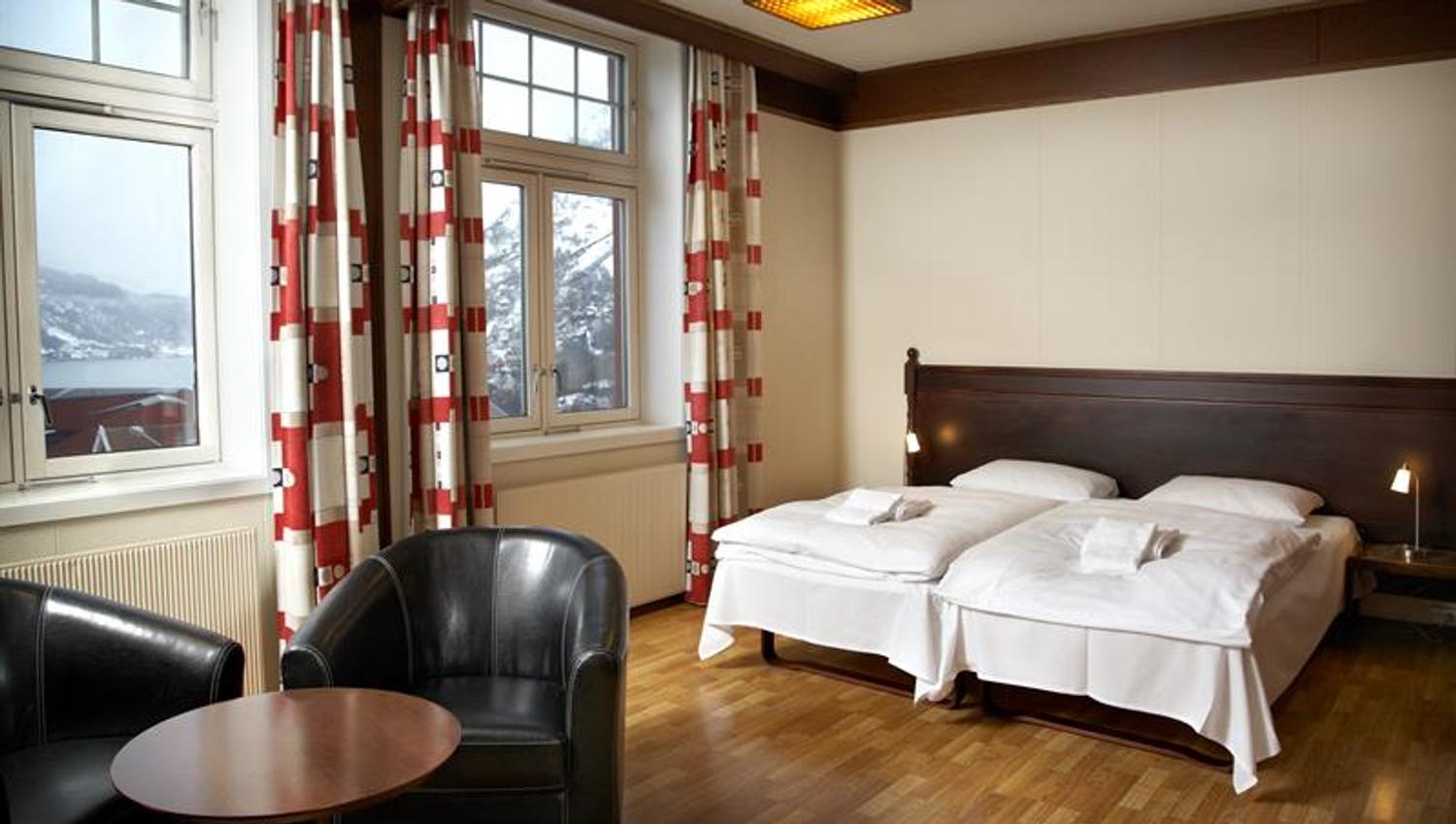 Spacious hotel room with large windows, classic decor, and views of the Hardangerfjord.