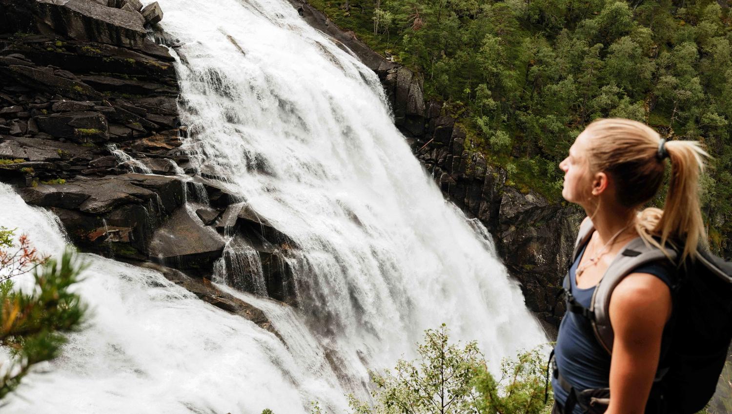 Close-up of a hiker overlooking Nykkjesøyfossen, one of Husedalen’s most stunning waterfalls.