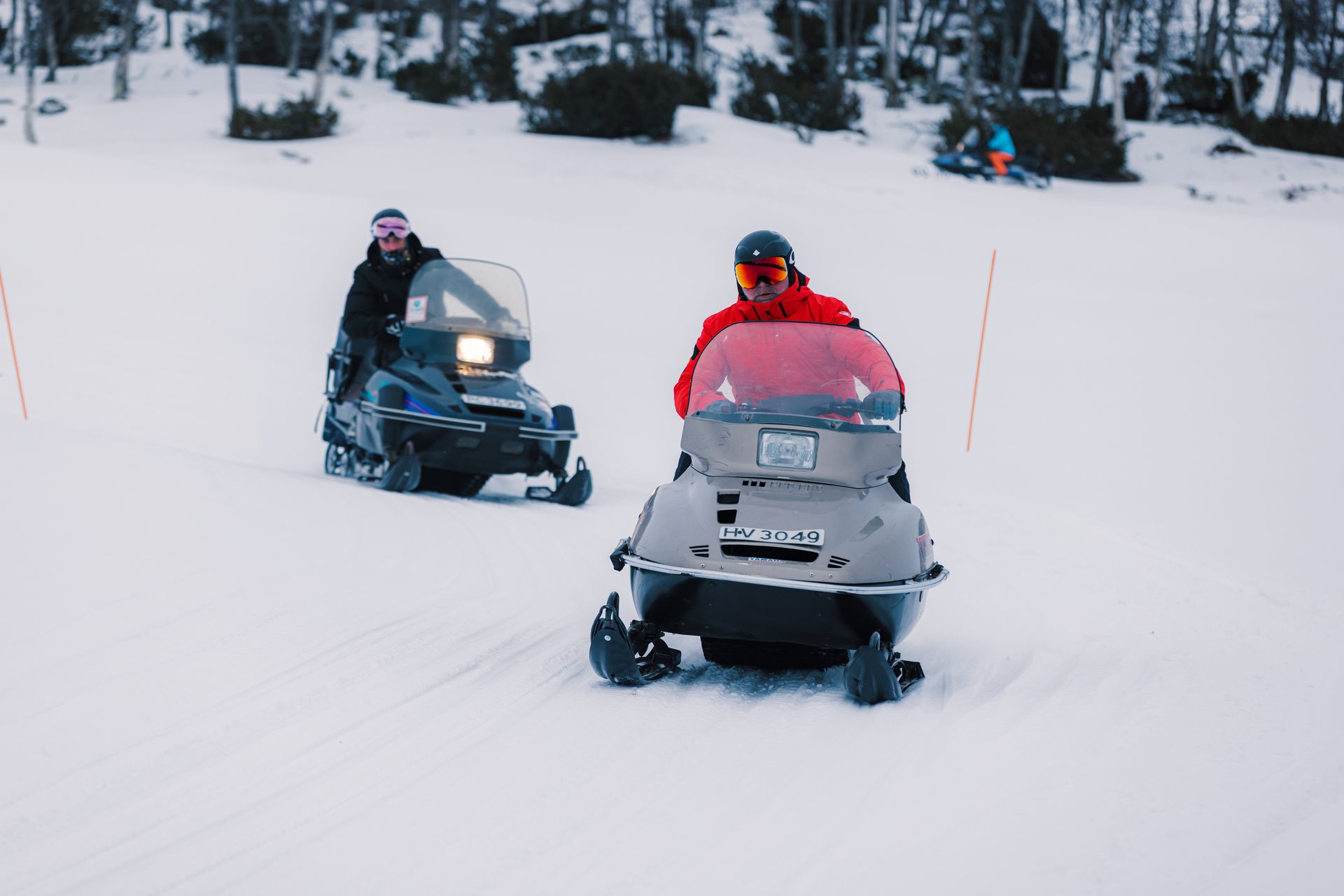 Two men on a snowmobile in a winter landscape.