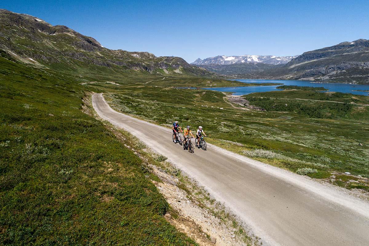 Cyclists on the climb on a gravel road to a mountain pass, with Jotunheimens high peaks in the background.