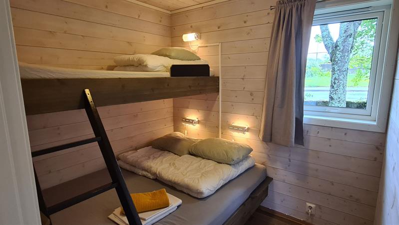 Simple and bright bedroom with bunk beds in a cabin at Trolltunga Camping.