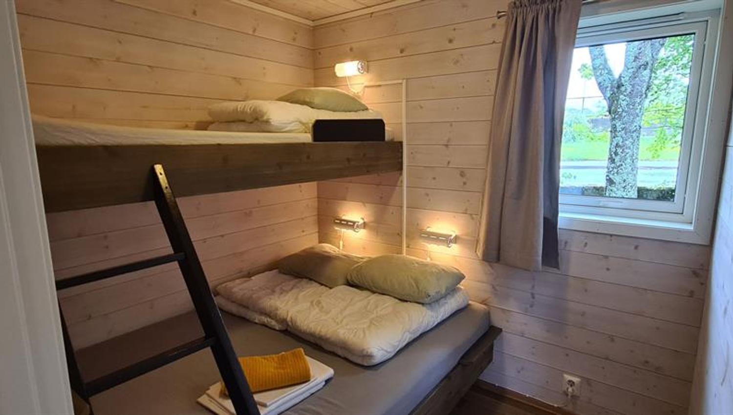 Simple and bright bedroom with bunk beds in a cabin at Trolltunga Camping.