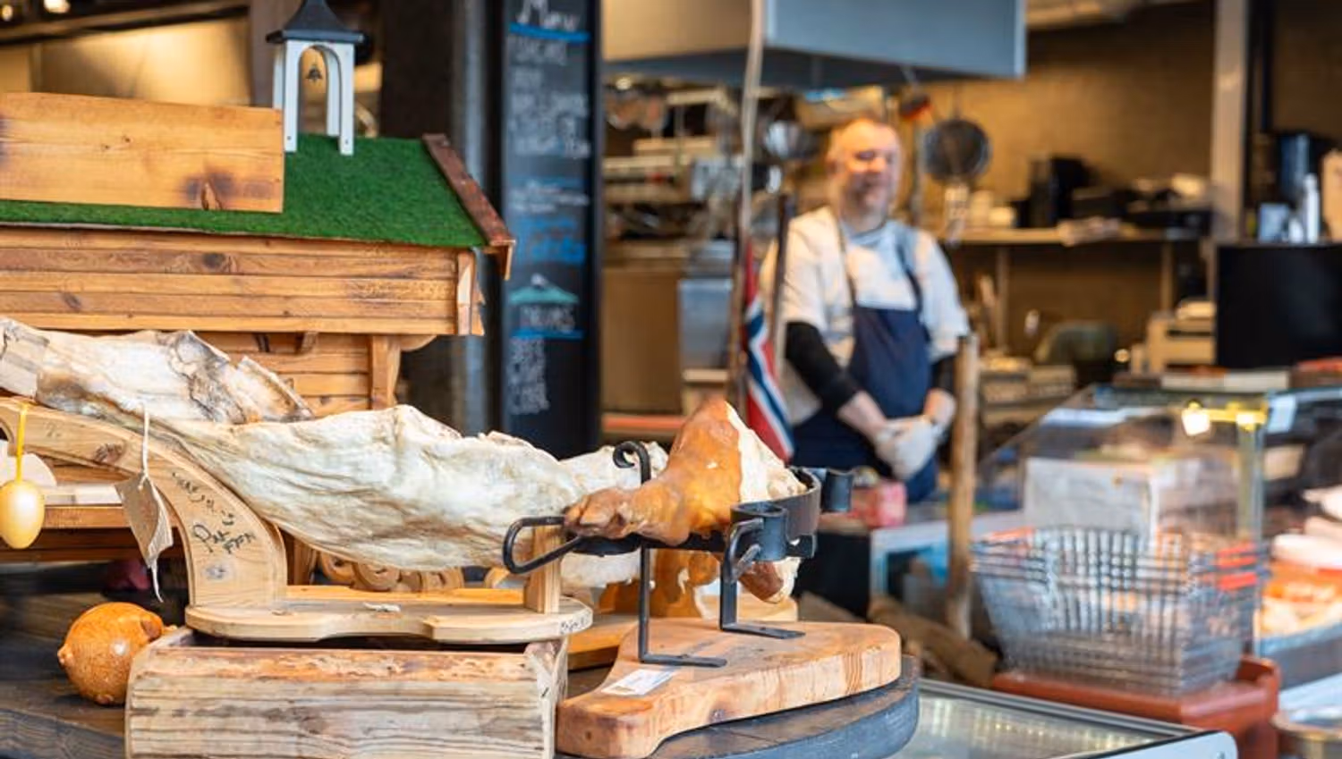 Shop interior with various hams, model of a traditional Norwegian storehouse, Norwegian flag and man