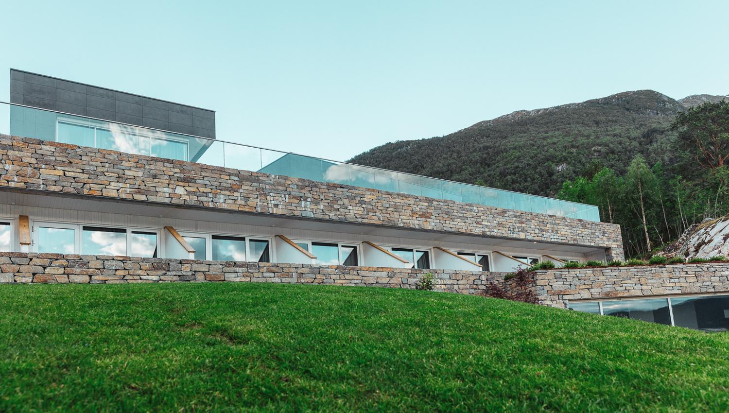 Natural stone walls at Hardanger House blended with lush landscape.