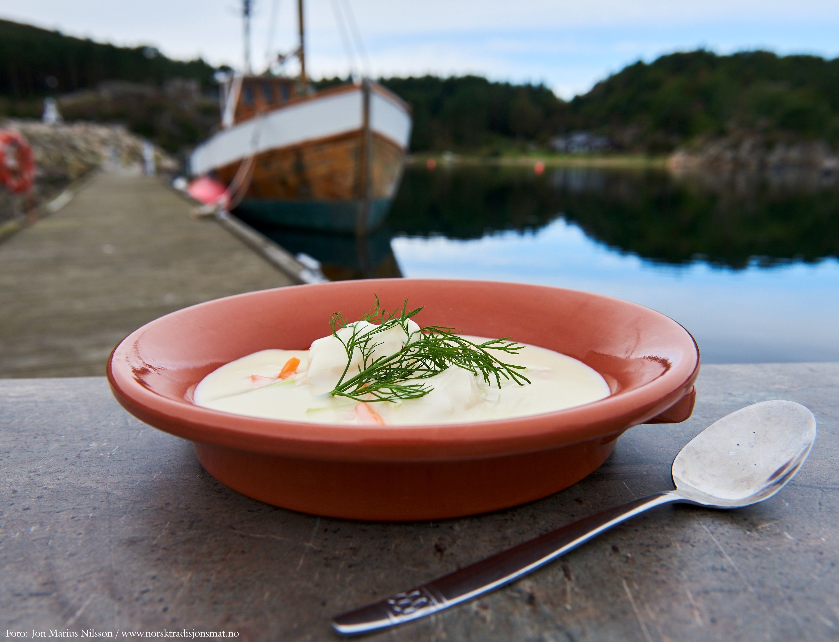 
Fish soup garnished with dill in an orange bowl