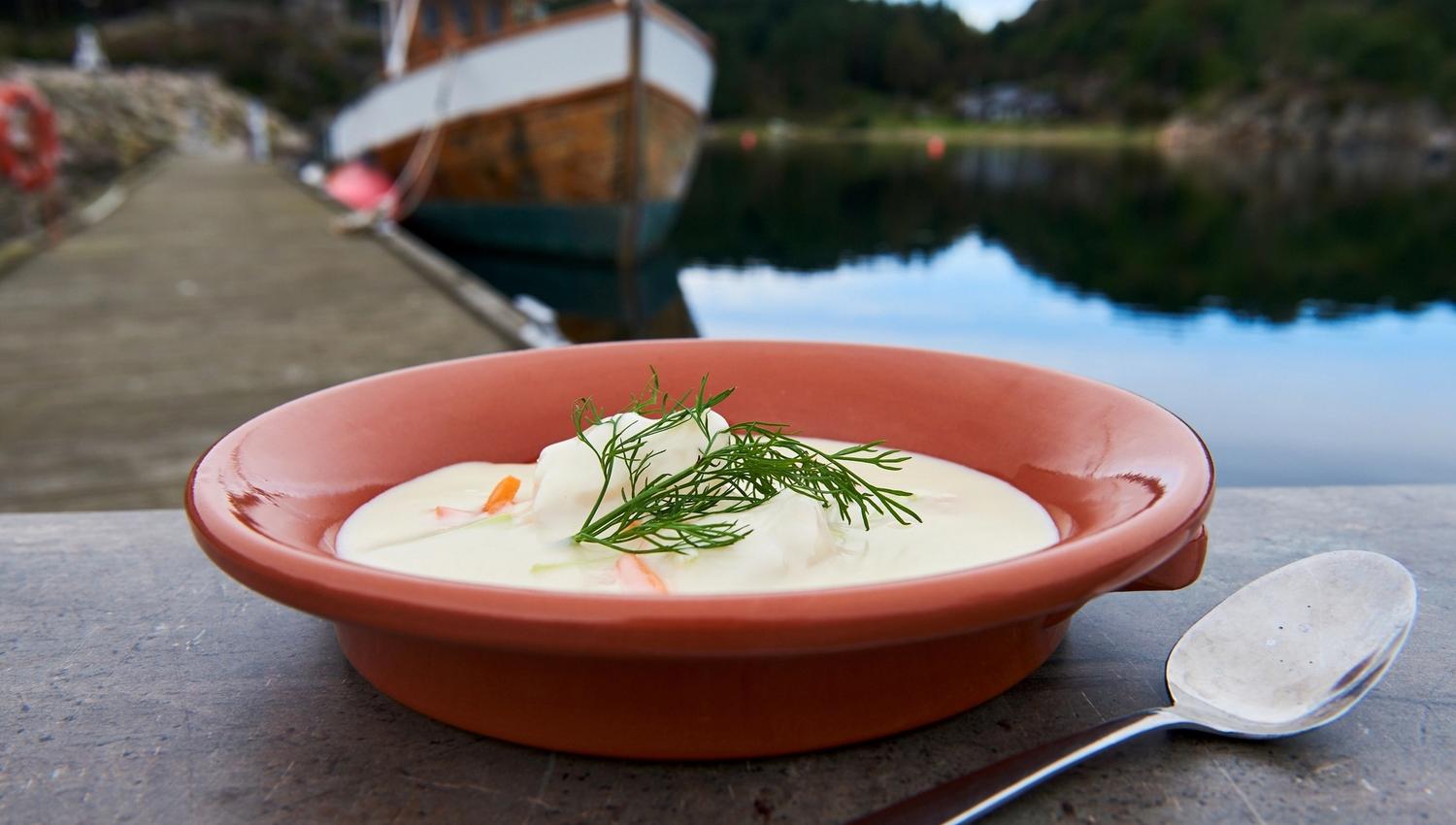 Fish soup garnished with dill in an orange bowl