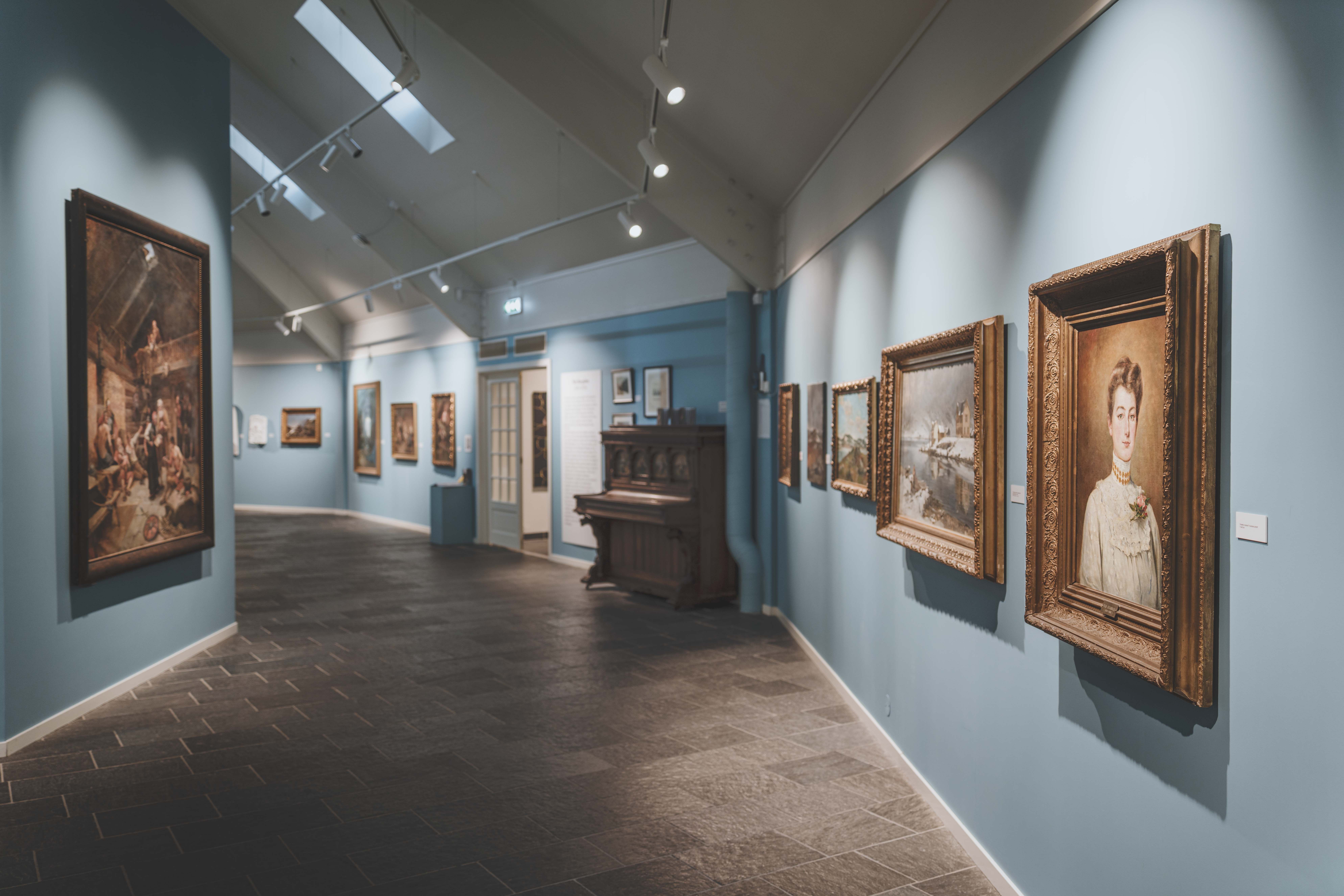 Paintings on the wall, and an old piano sitting by the entrance.