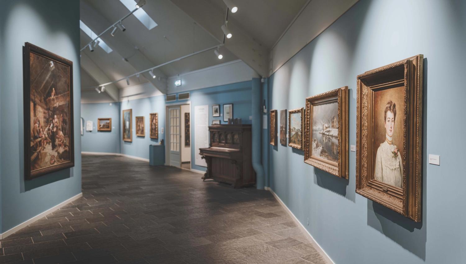 Paintings on the wall, and an old piano sitting by the entrance.