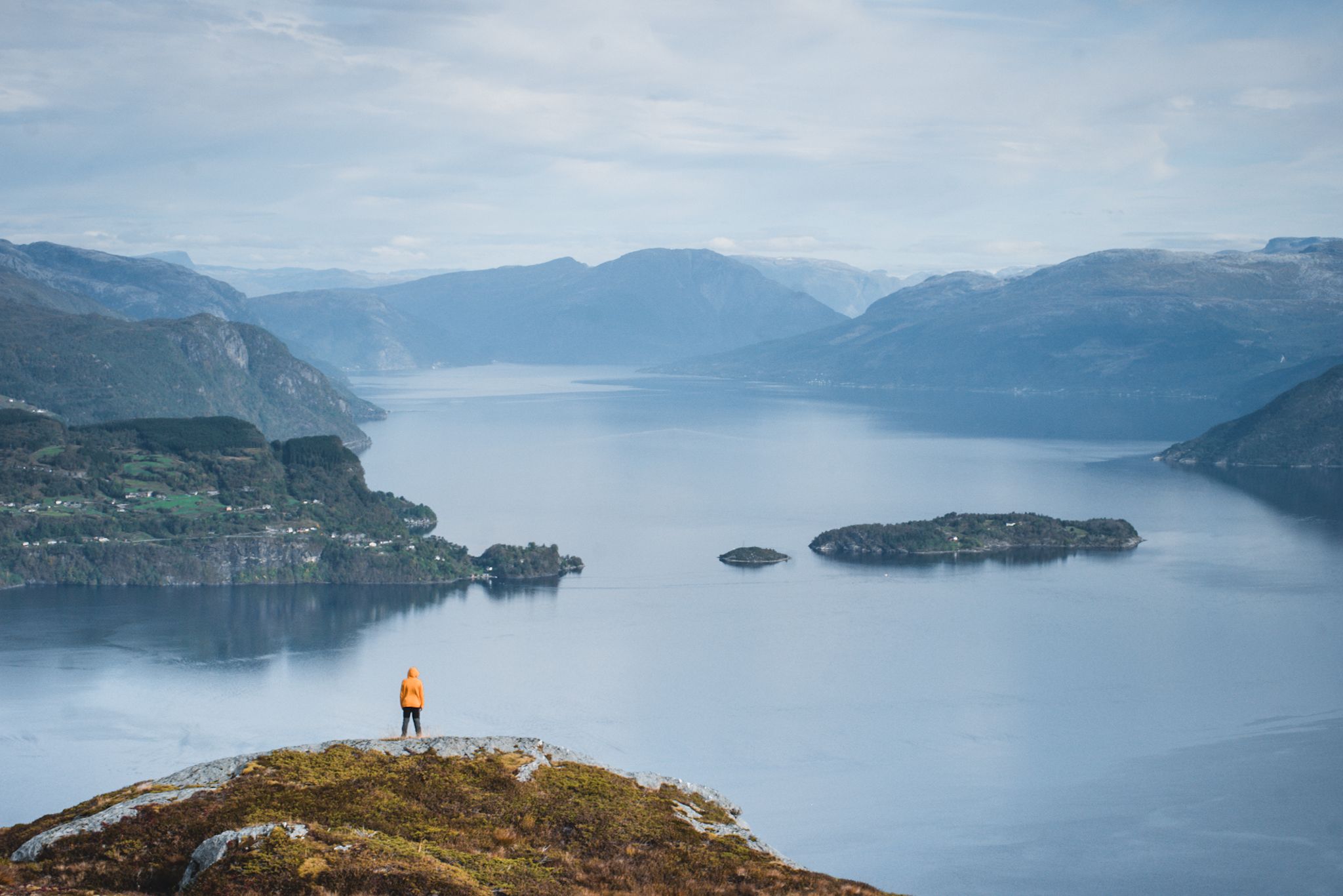 Hiker standing on a cliff overlooking the vast Hardangerfjord.