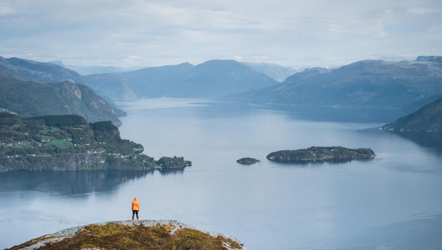 Hiker standing on a cliff overlooking the vast Hardangerfjord.