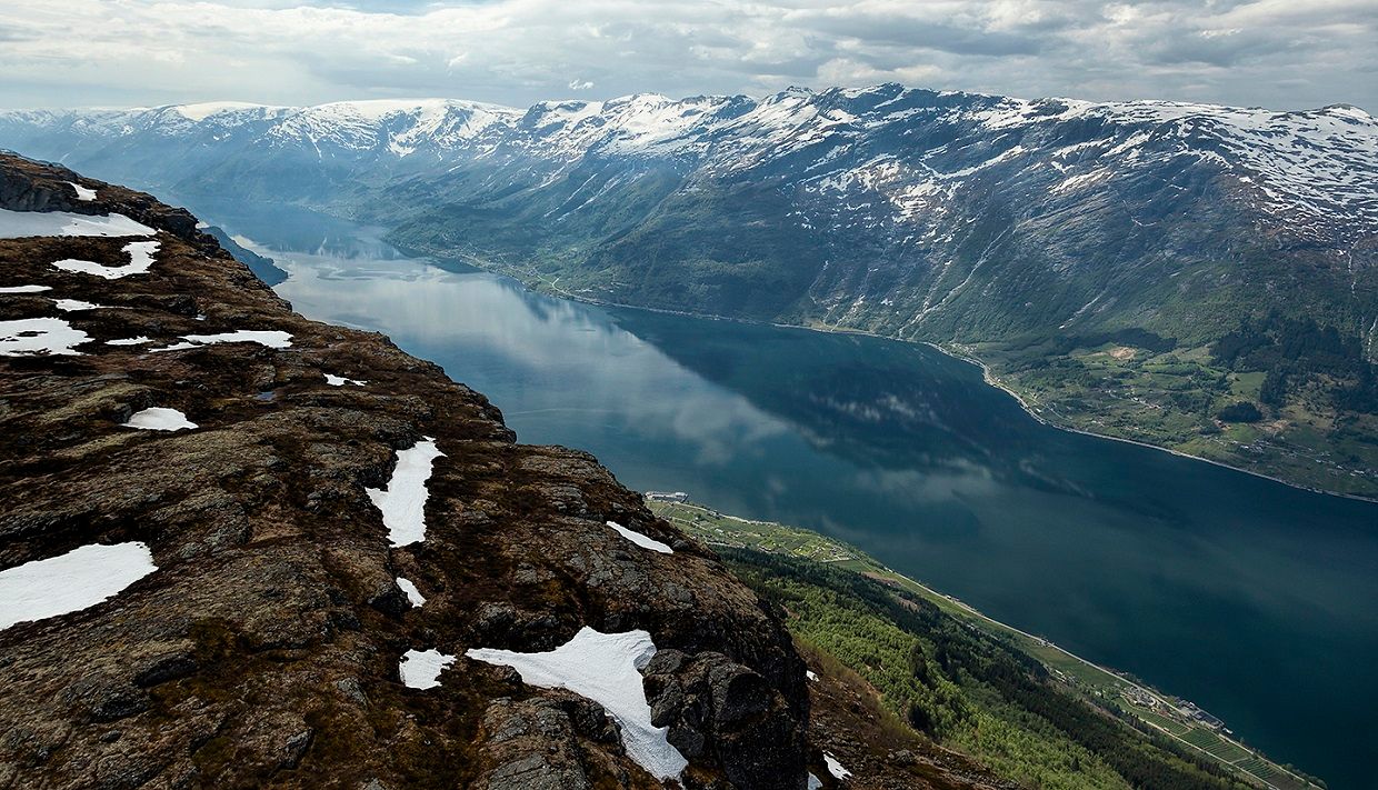 Utsikt frå Dronningstien over Sørfjorden med snødekte fjell i bakgrunnen.