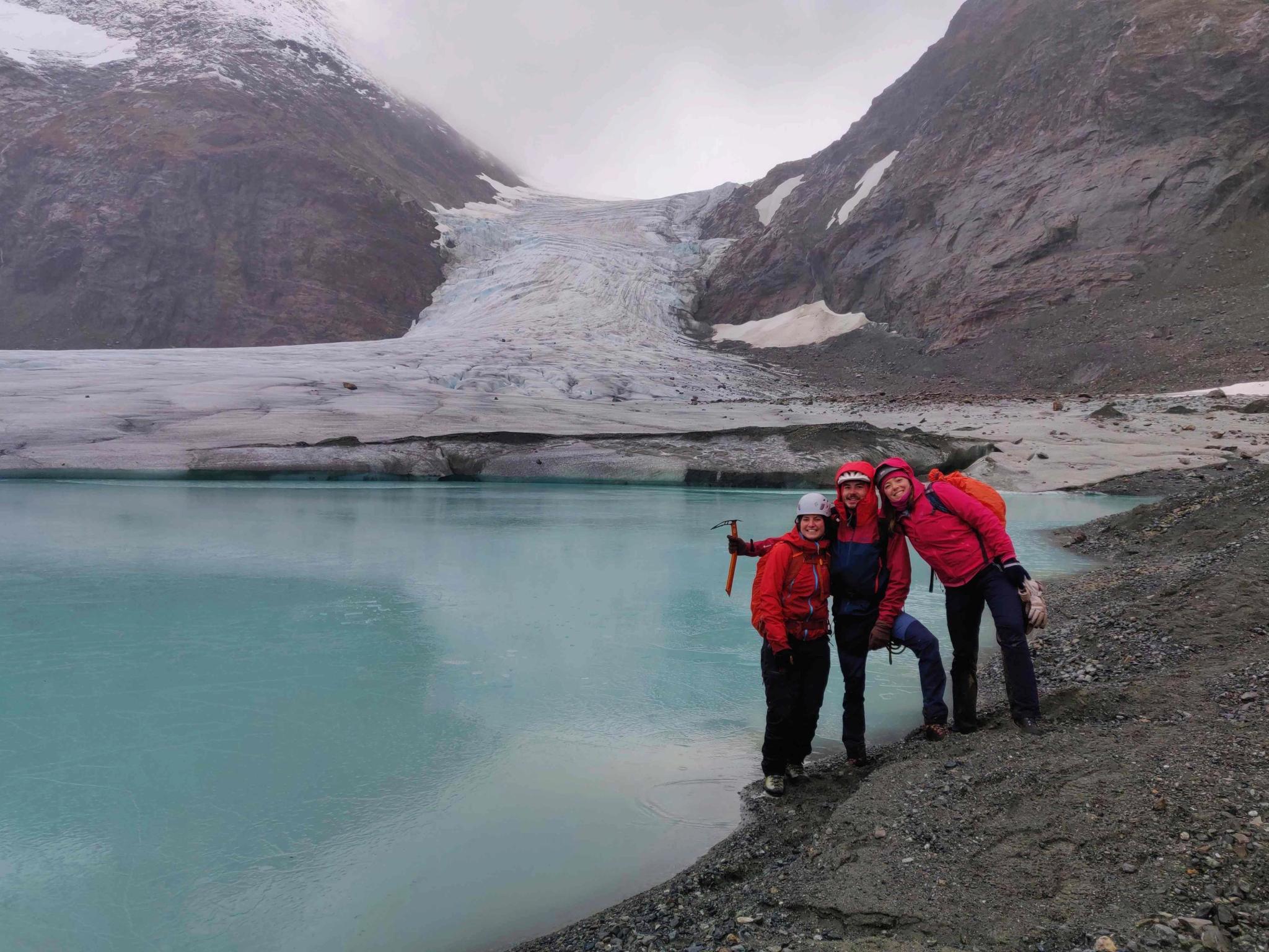 Three persons in front of a glacier.