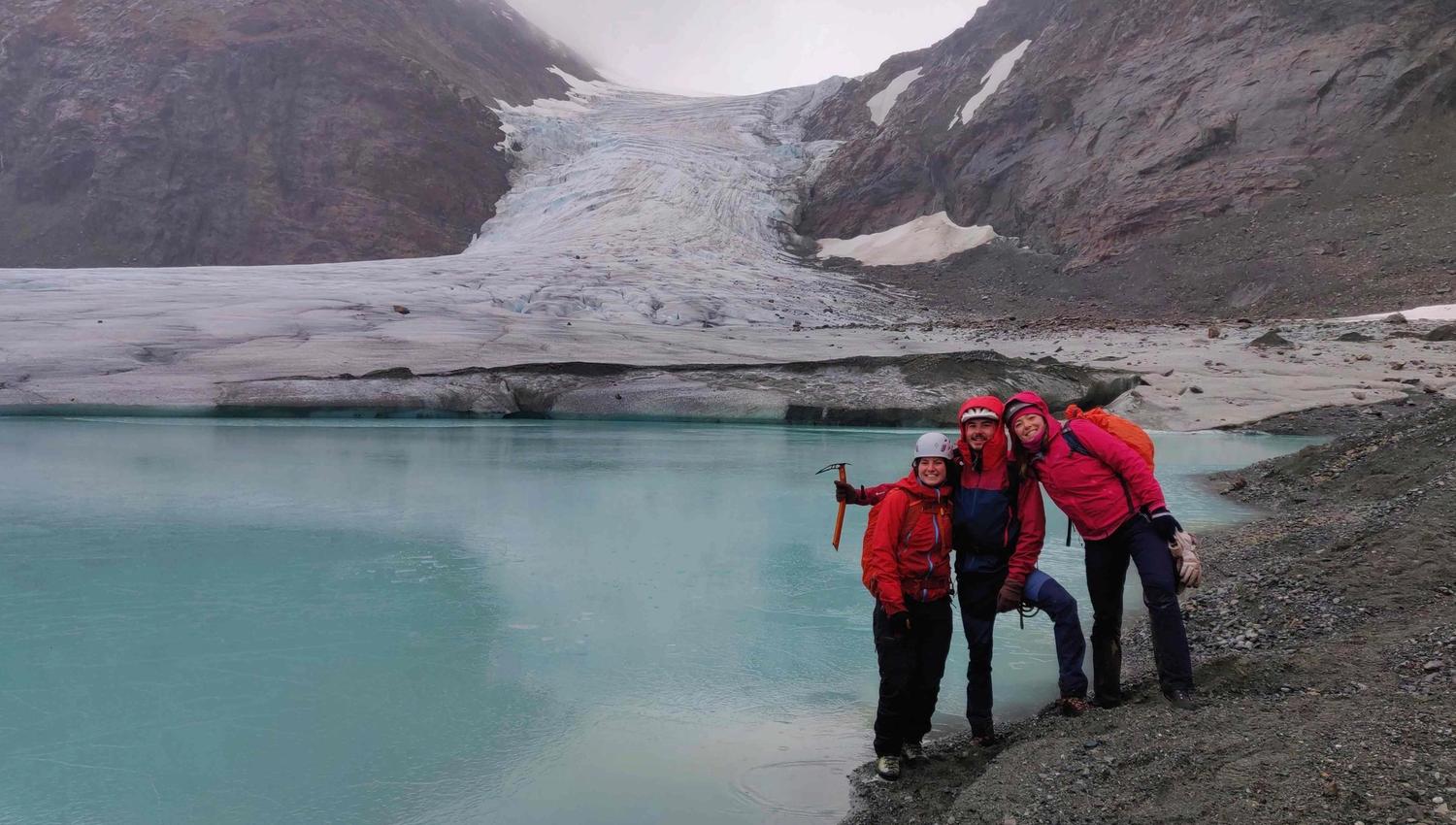 Three persons in front of a glacier.