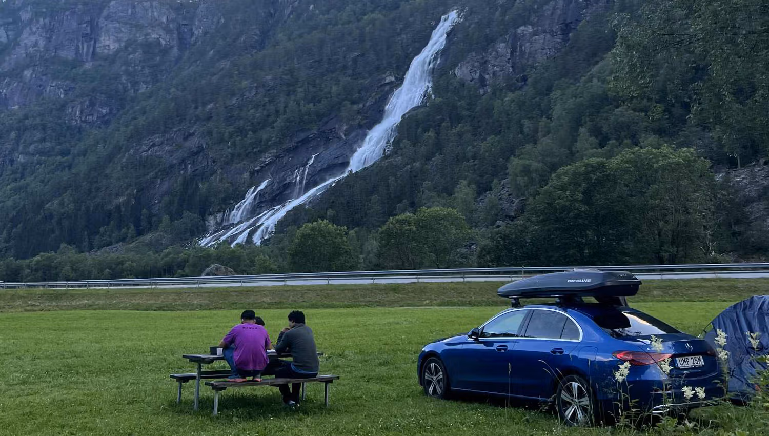 Gäste genießen den Blick vom Hildal Camping auf den Wasserfall und die Berge im Oddatal.