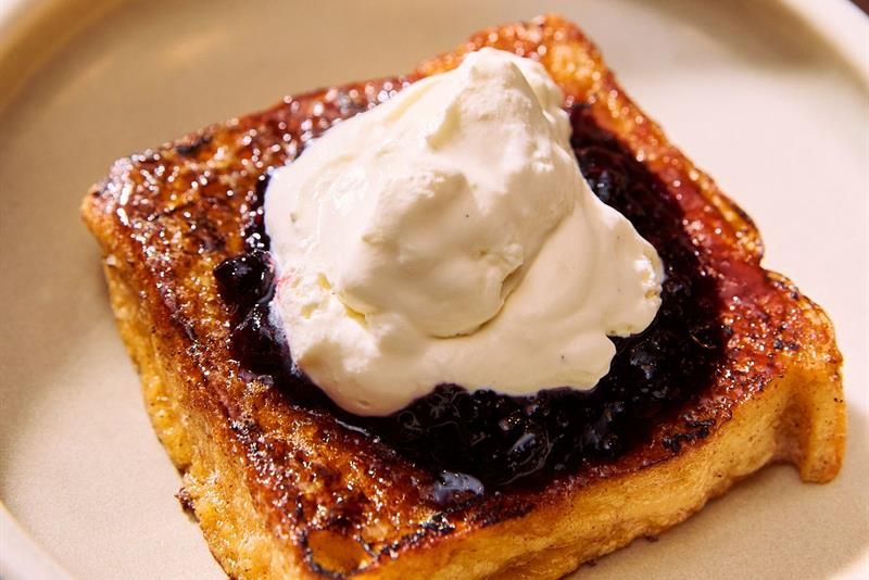 The dish consists of toasted bread topped with cream and berries. It is served as part of the breakfast or dessert offering.
