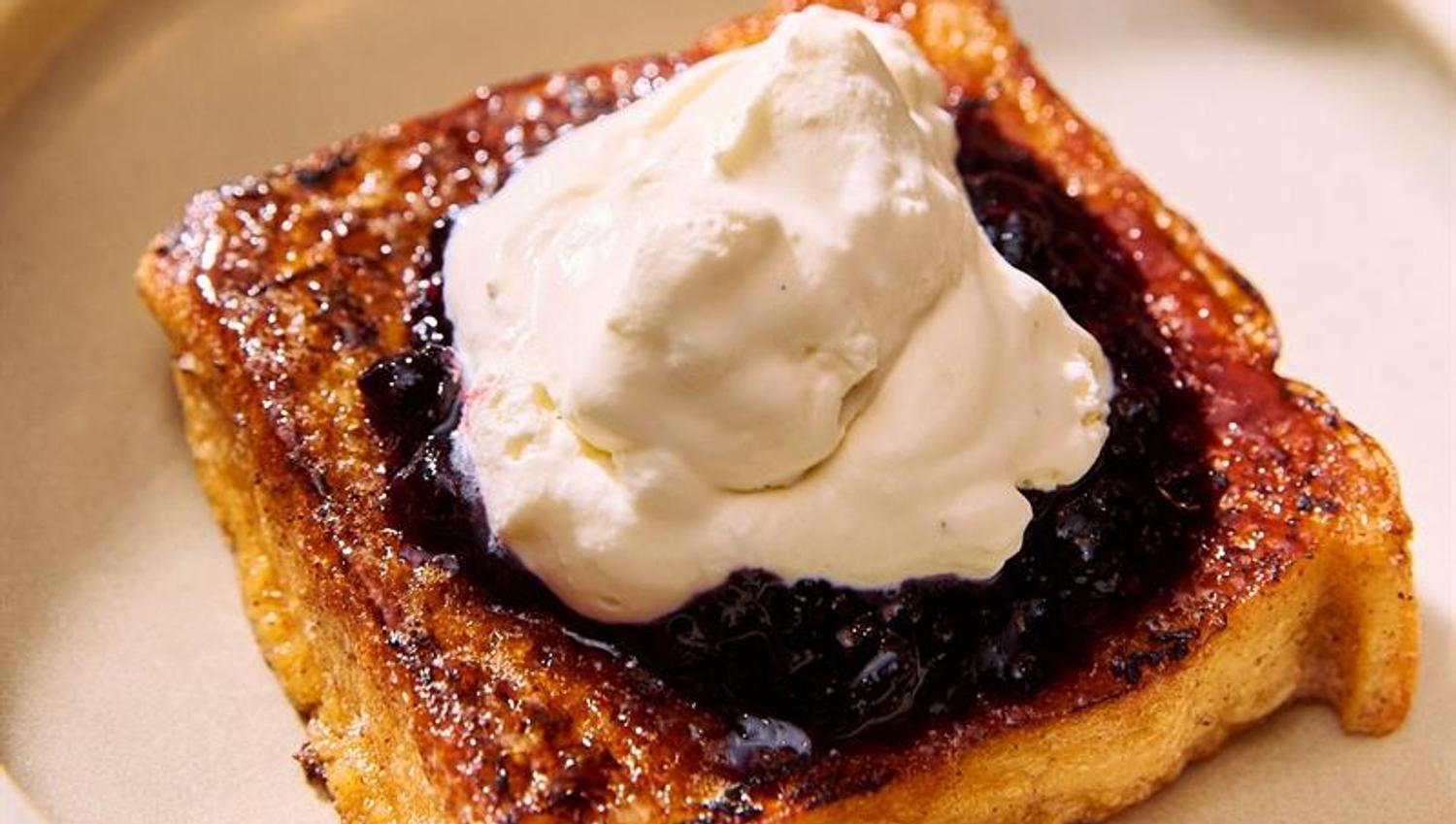 The dish consists of toasted bread topped with cream and berries. It is served as part of the breakfast or dessert offering.