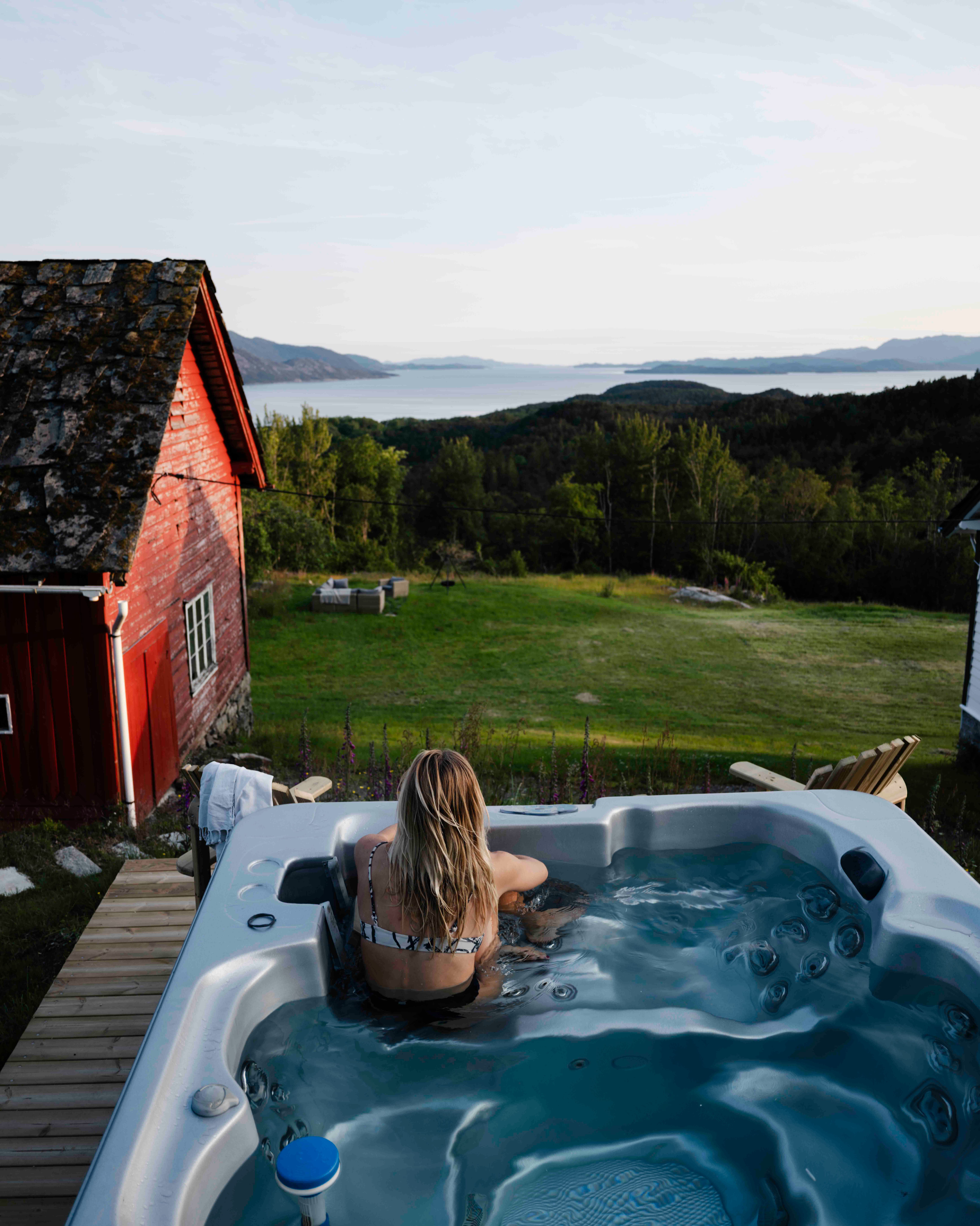 Woman relaxing in the outdoor hot tub overlooking the Hardangerfjord at Stigen Fjordlodge.