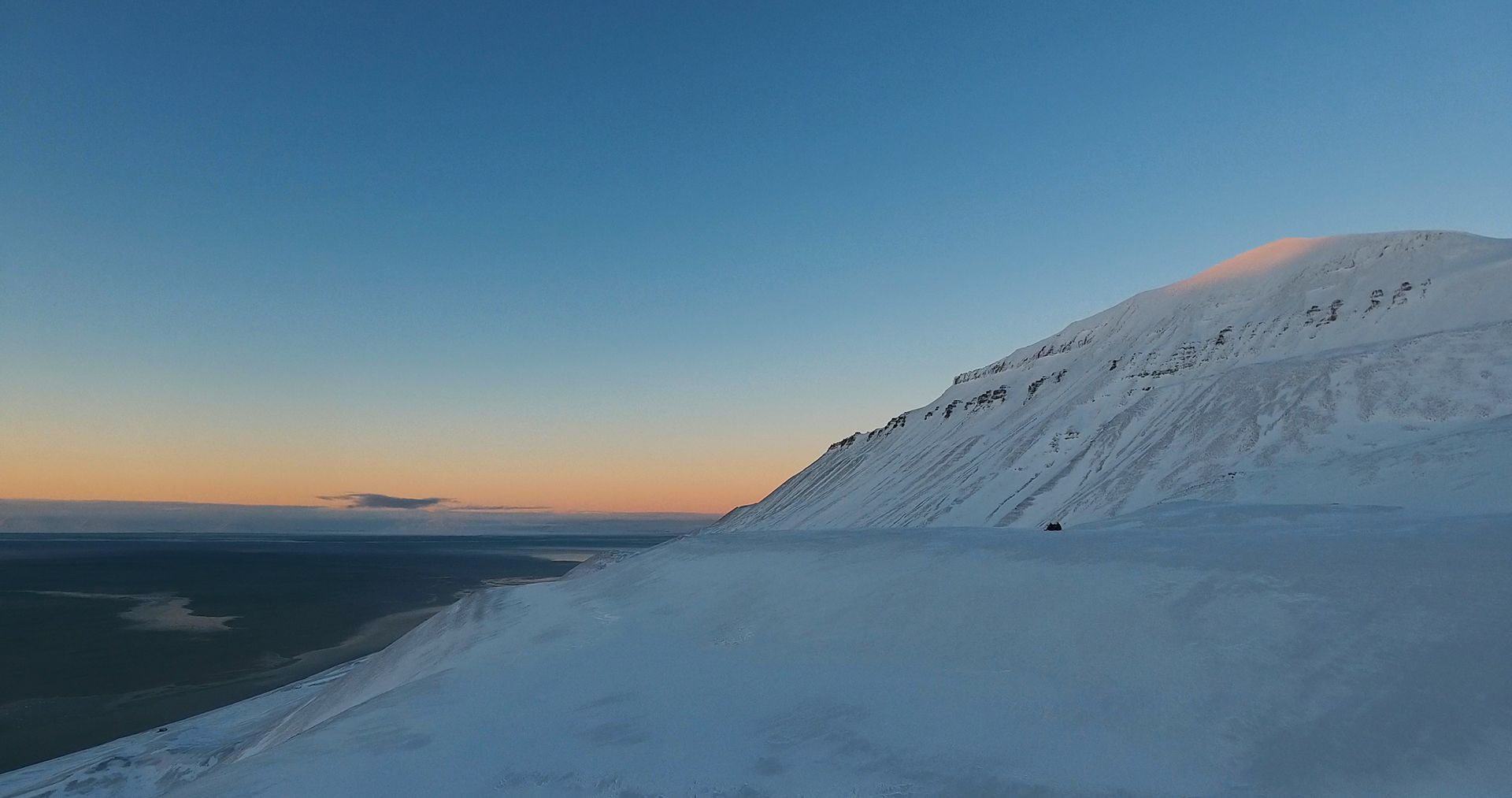 Solstråler fra midnattssola som treffer en fjelltopp