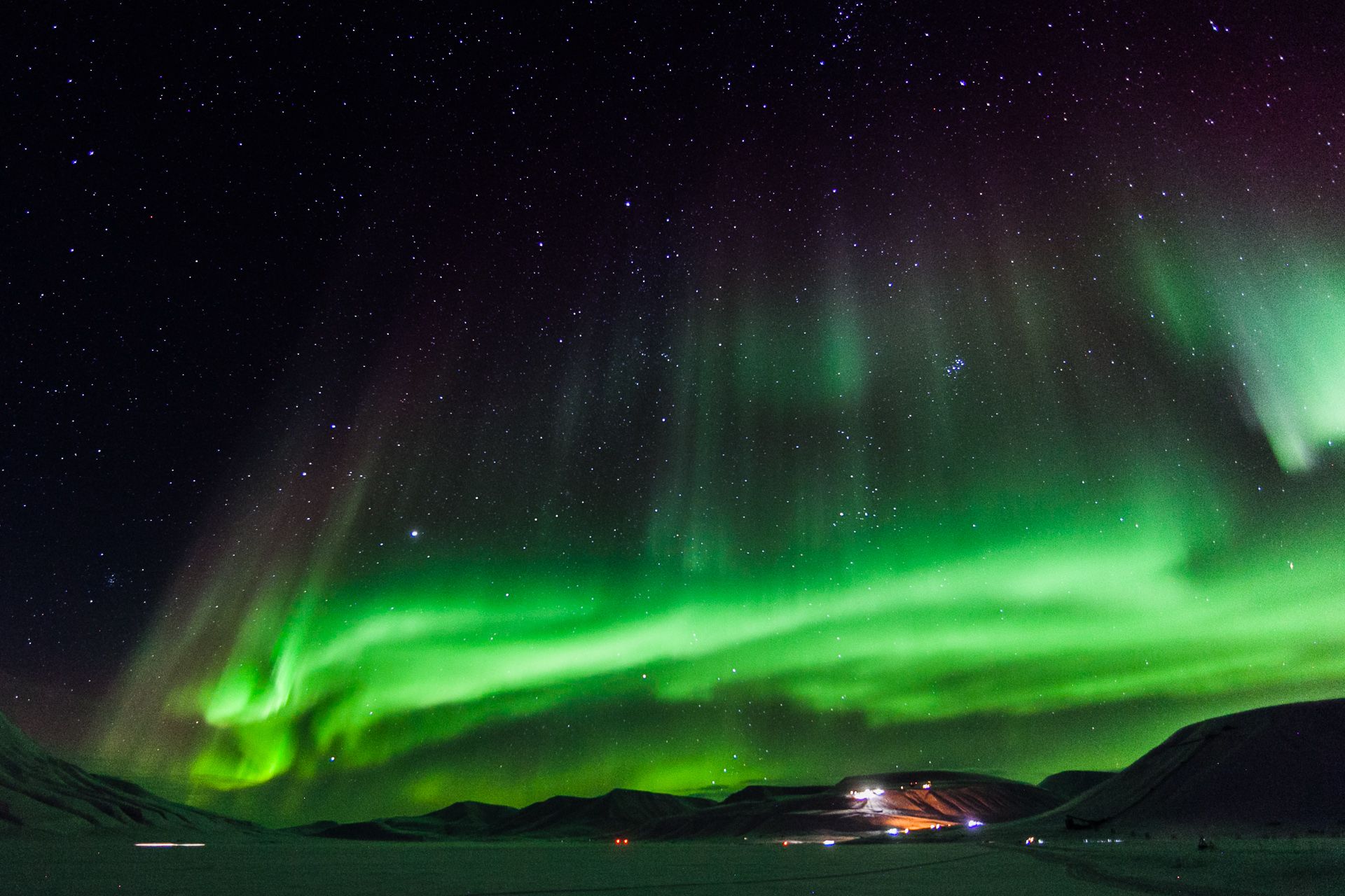 Northern lights shining in the skies above a valley
