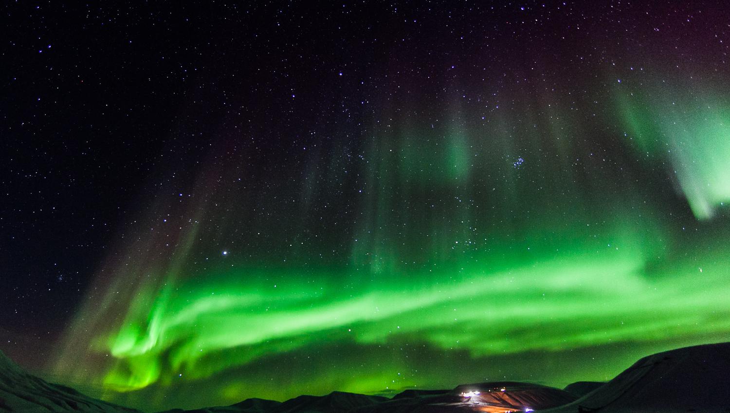 Northern lights shining in the skies above a valley