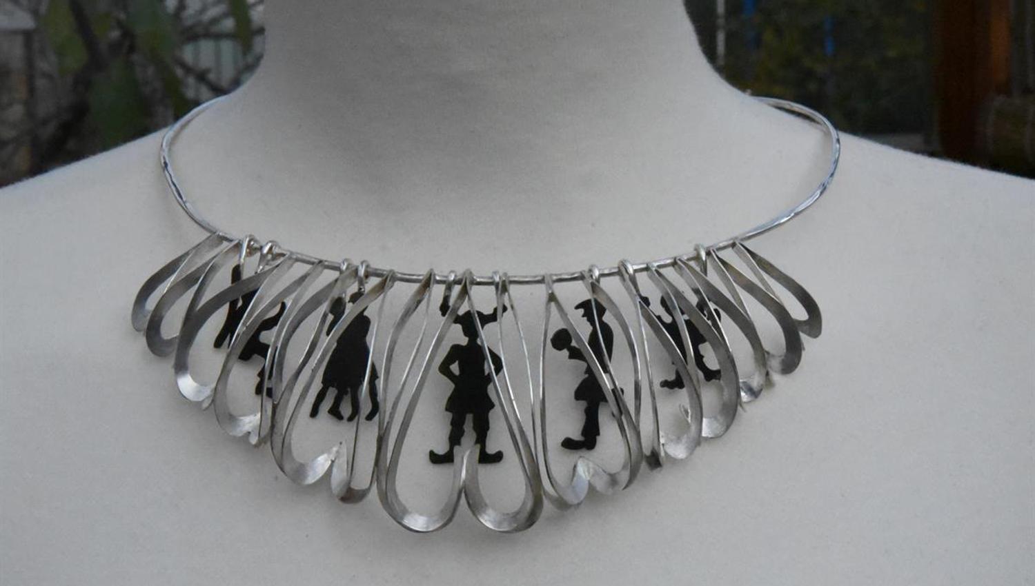 Metal and glass necklace with decorative hanging shapes.
