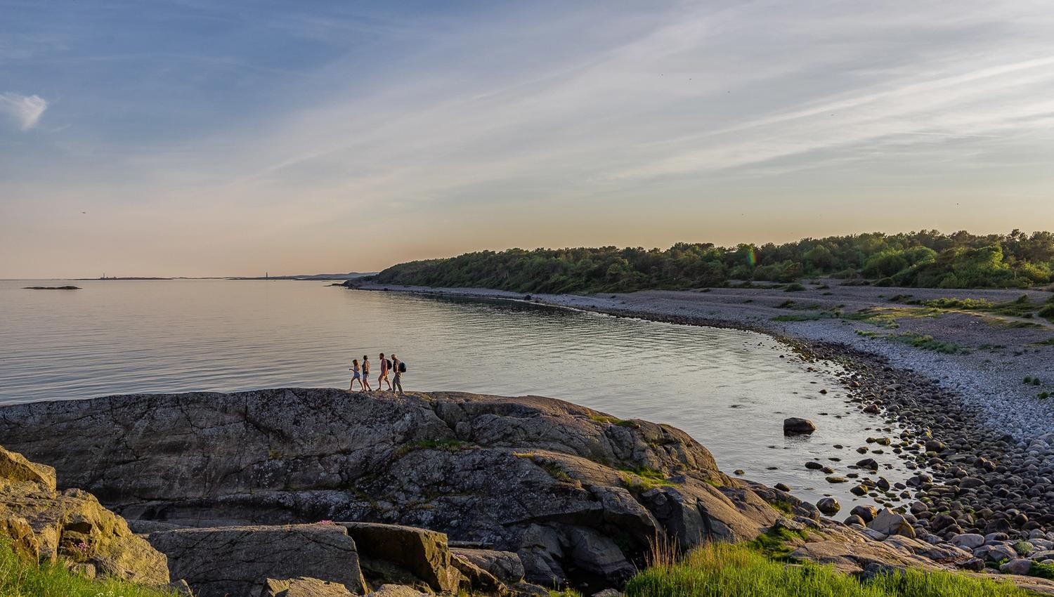 4 men on their way over the rocks in the Raet national park by Spornes beach on Tromøy outside Arendal to take a morning bath in May.