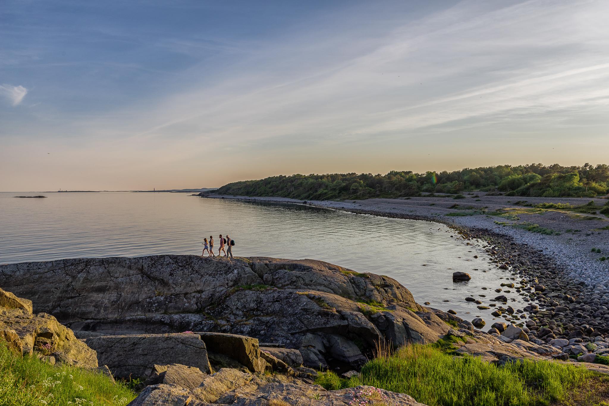 4 men on their way over the rocks in the Raet national park by Spornes beach on Tromøy outside Arendal to take a morning bath in May.