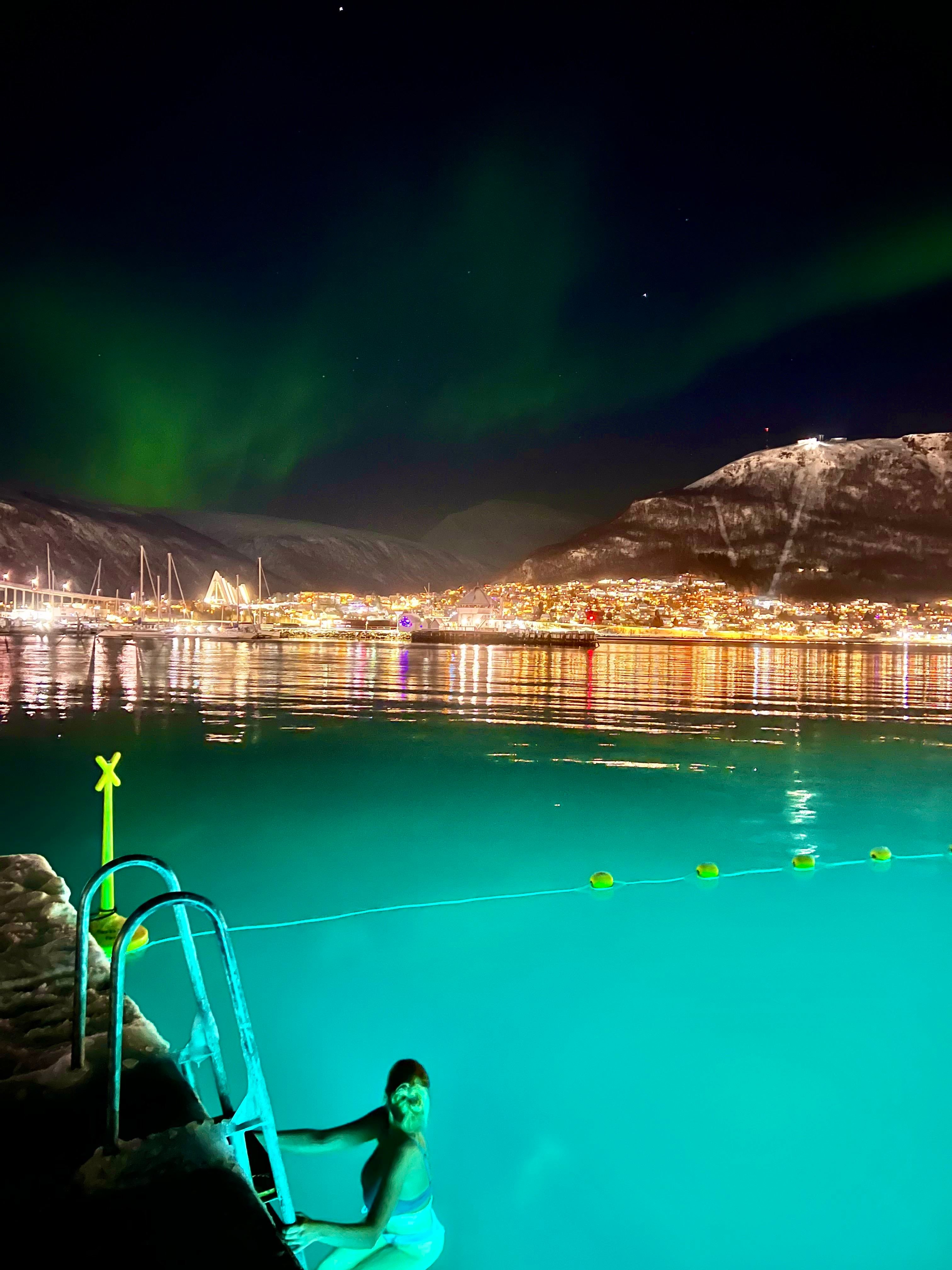 A person swimming under the Northern Lights