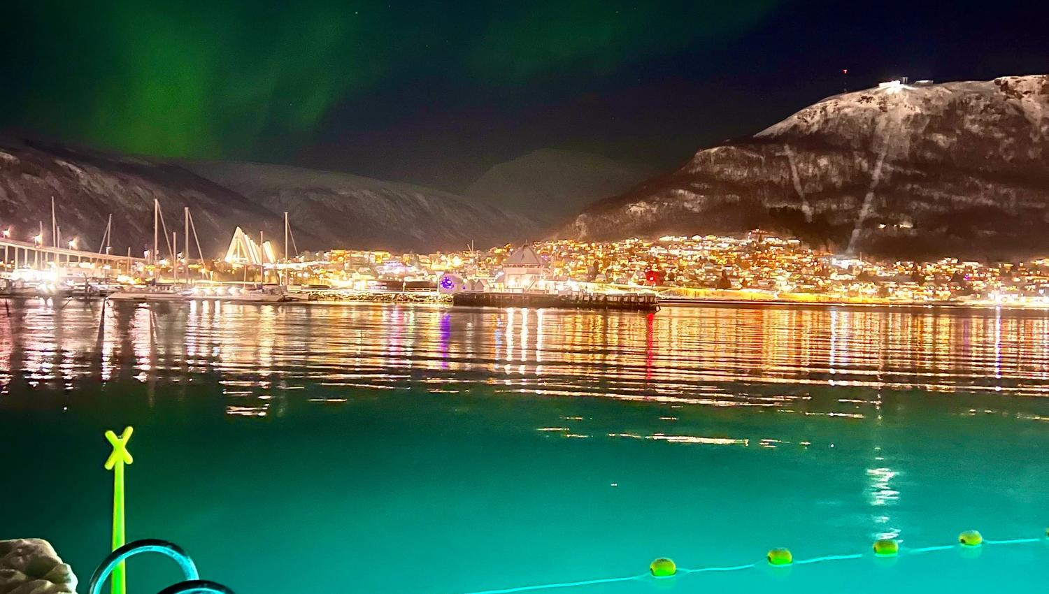 A person swimming under the Northern Lights