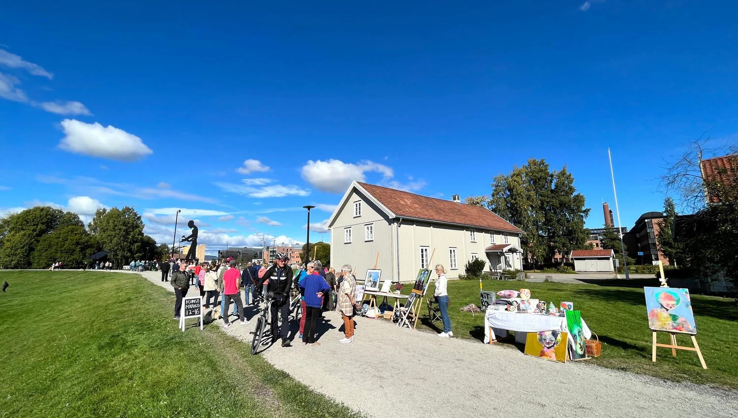 mennesker som går på en vei med et grått hus i bakgrunnen