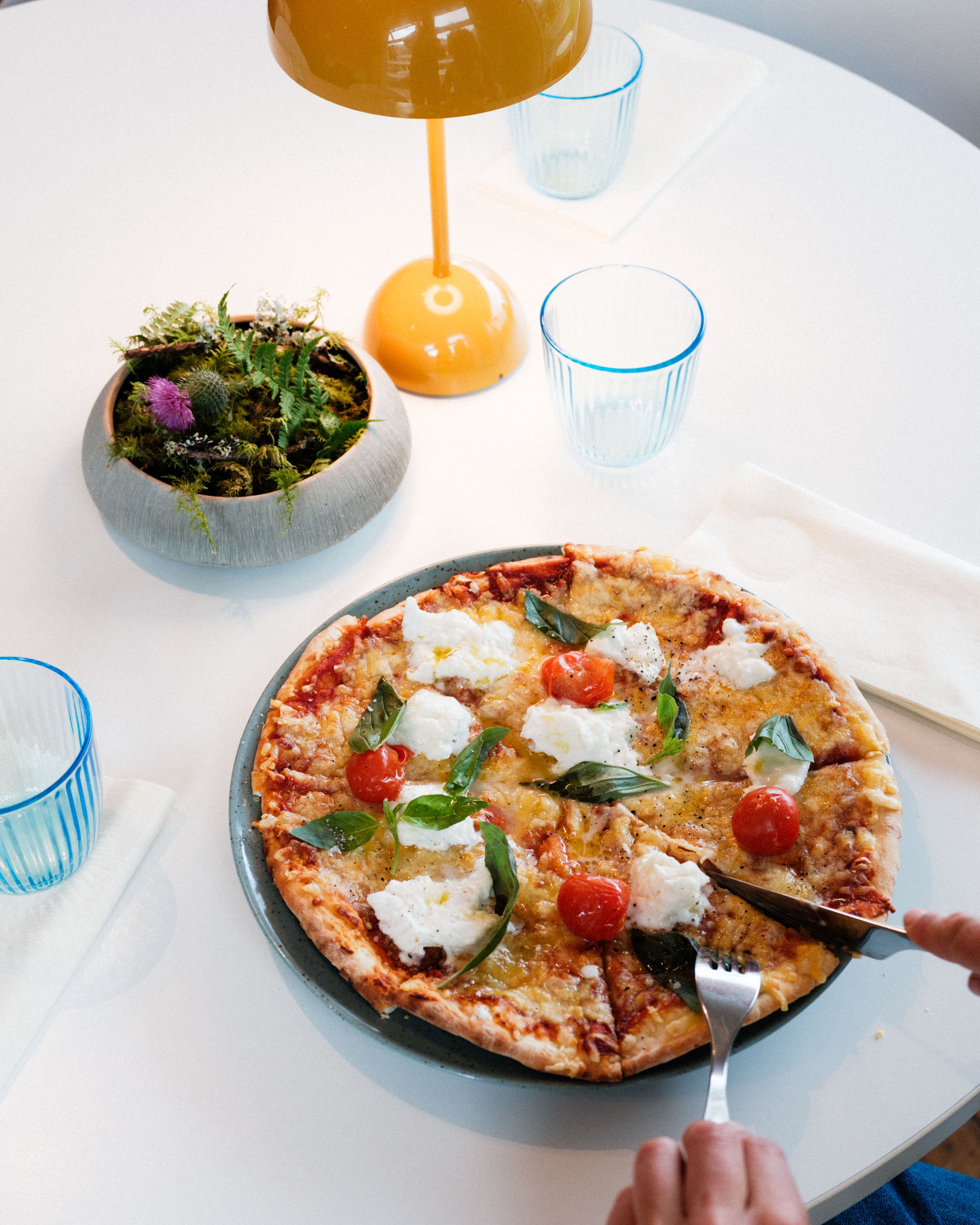 Stone oven-baked pizza with fresh basil, cherry tomatoes and soft cheese at Gløyp Spiseri.