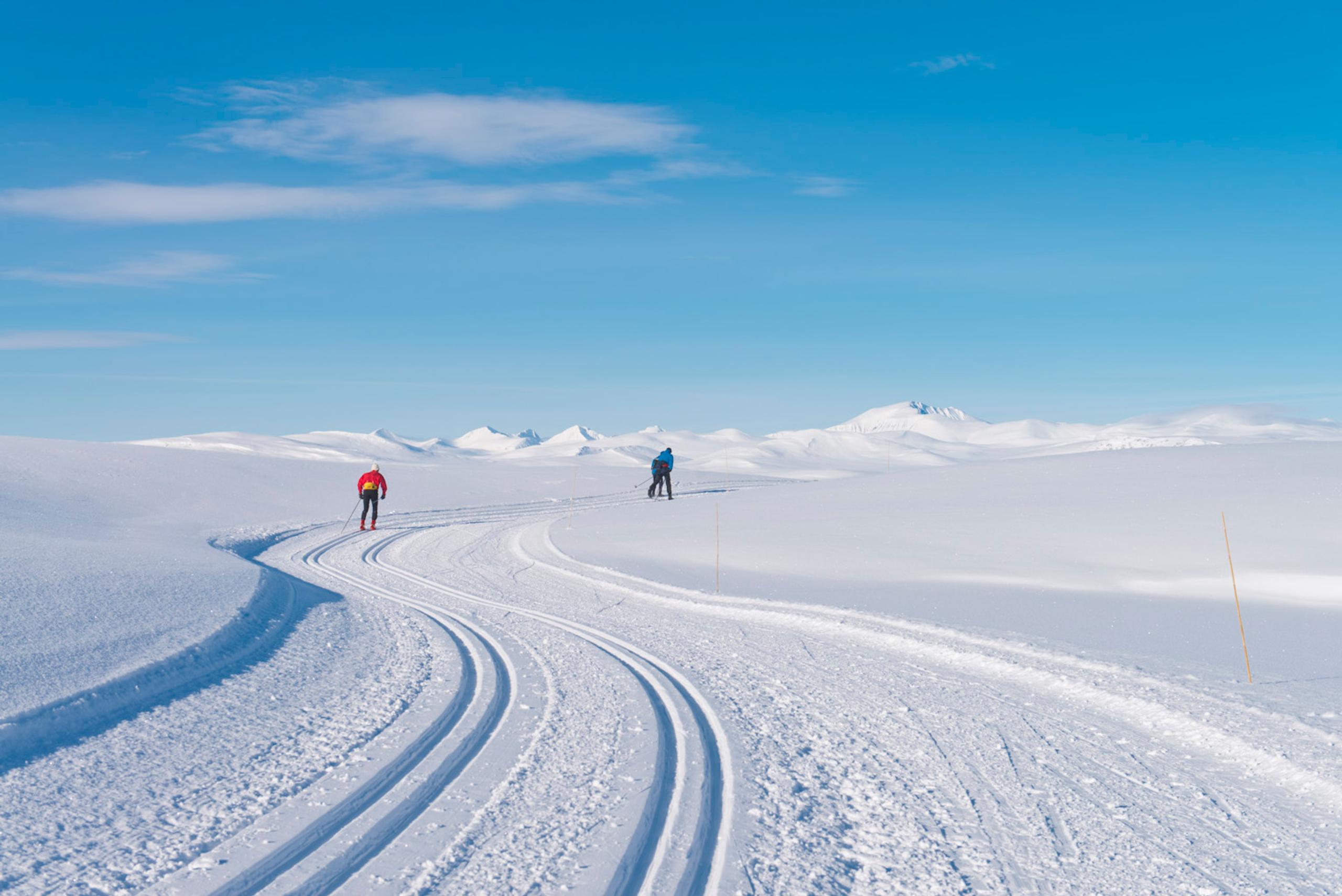Mountains and cross country skiers on a bluebird day. The peaks of Rondane in view. Spidsbergseter Resort Rondane