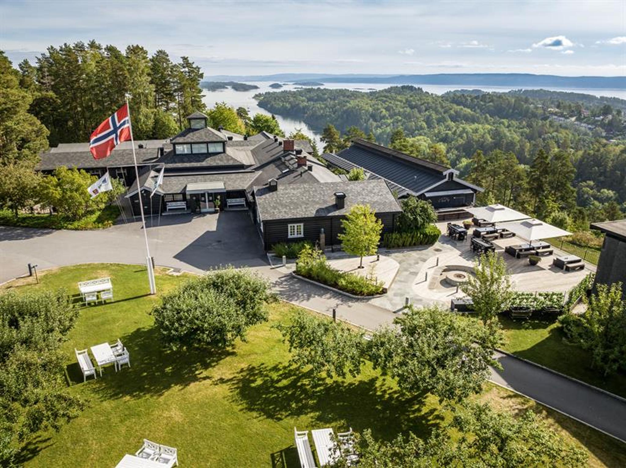 Oversiktsbilde av hotellet med fjord og skog i bakgrunn